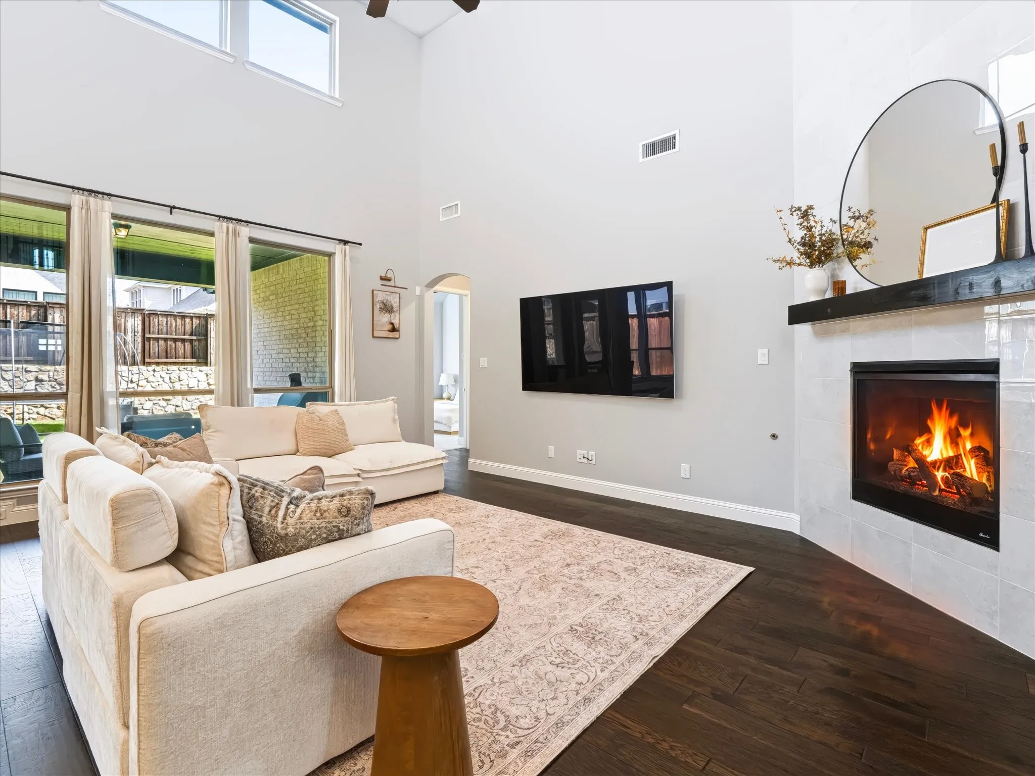 Vaulted ceilings, wood-finish flooring, a contemporary fireplace with a dark wood mantel, and multiple large windows