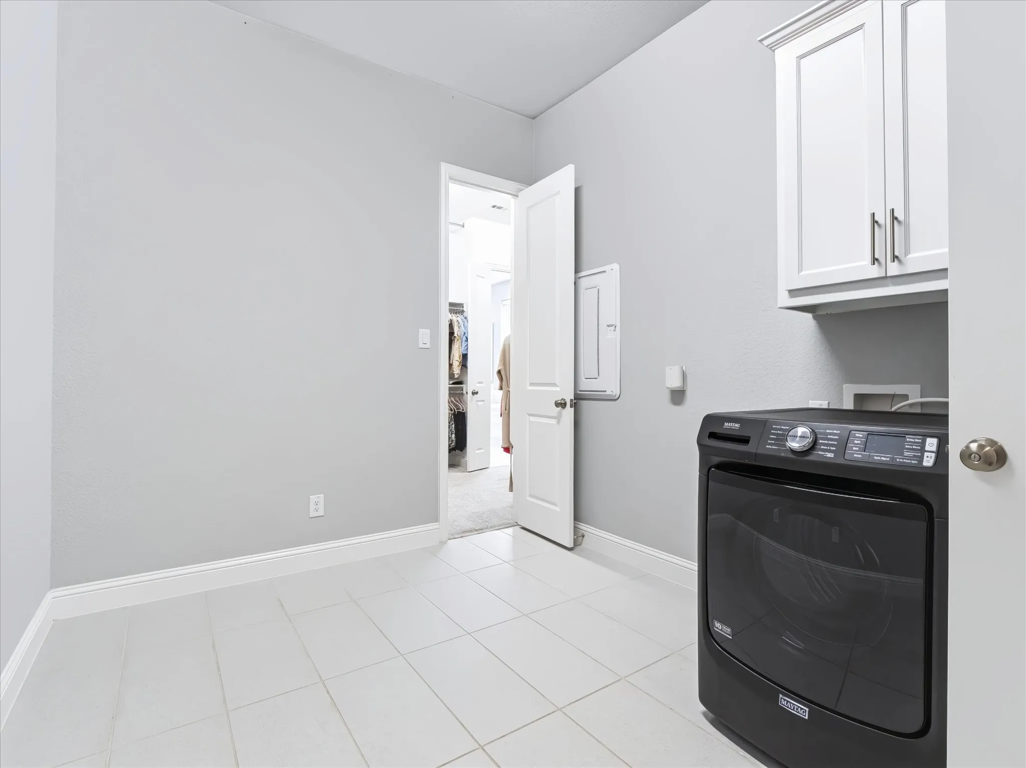 Light gray wall color, white floor tiling, white overhead cabinetry, white trim, and a white door