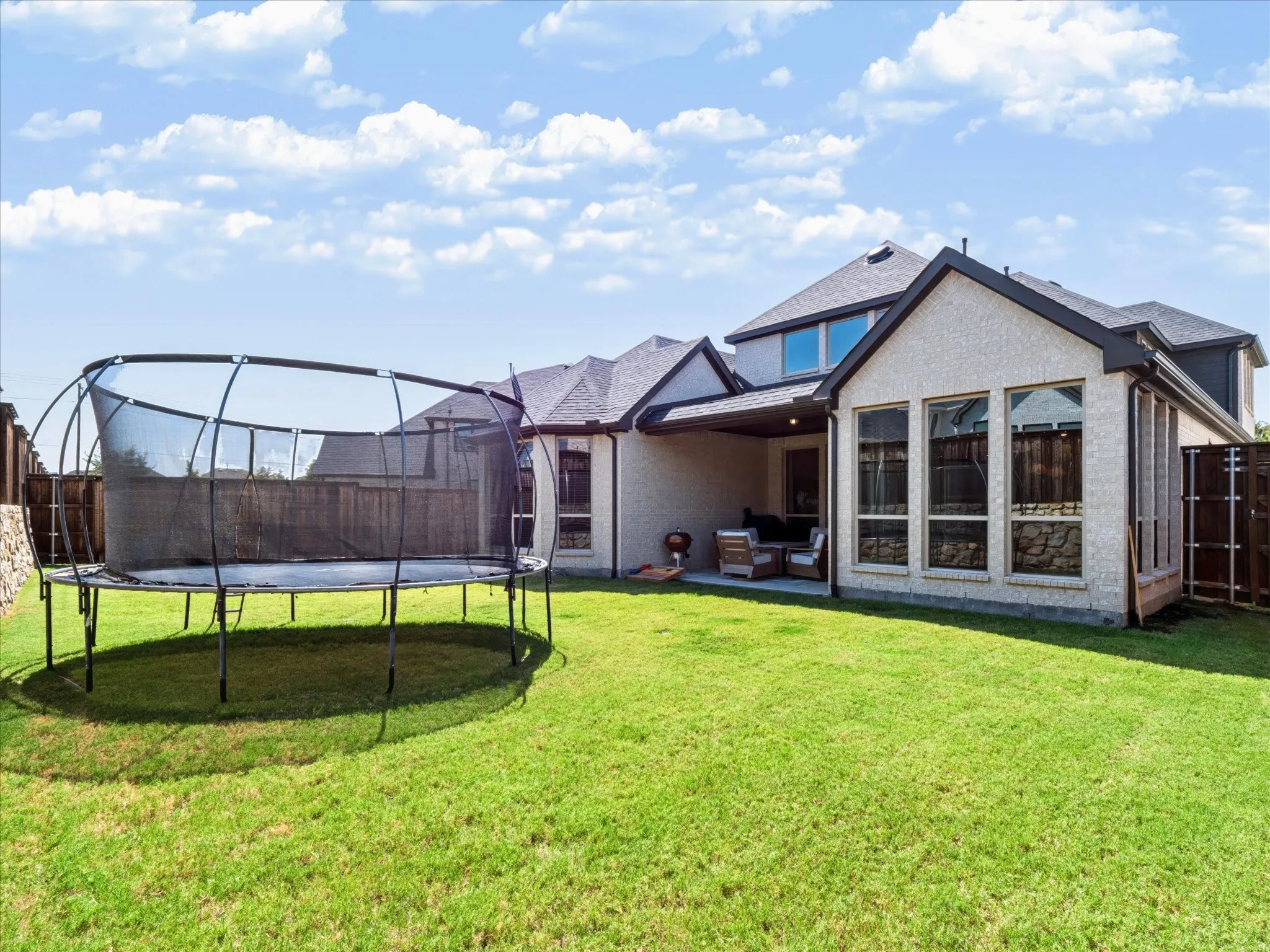 Expansive green lawn with a covered patio area and partial privacy fencing