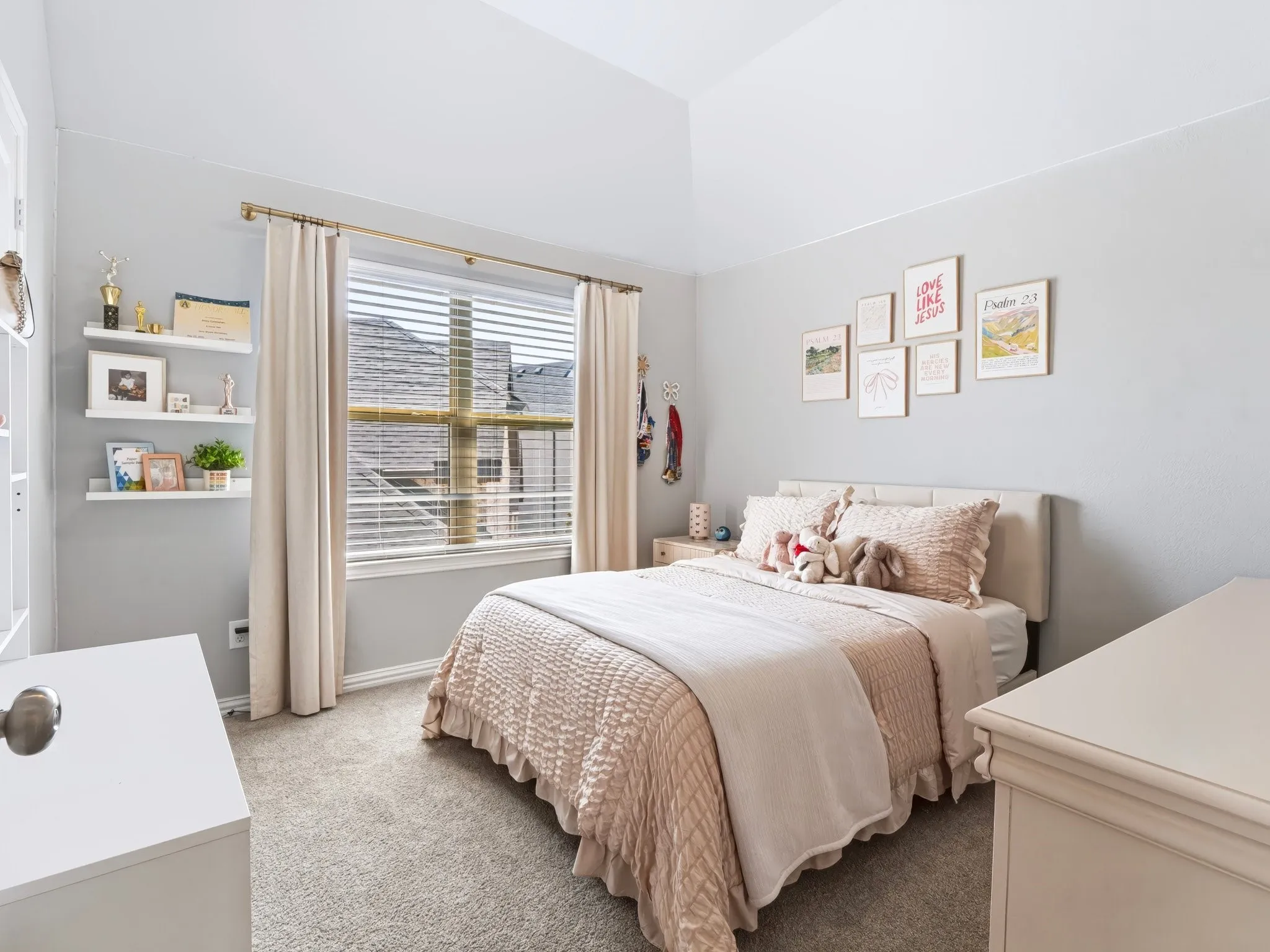 Vaulted ceiling, carpet flooring, a large window with blinds, and built-in wall shelving
