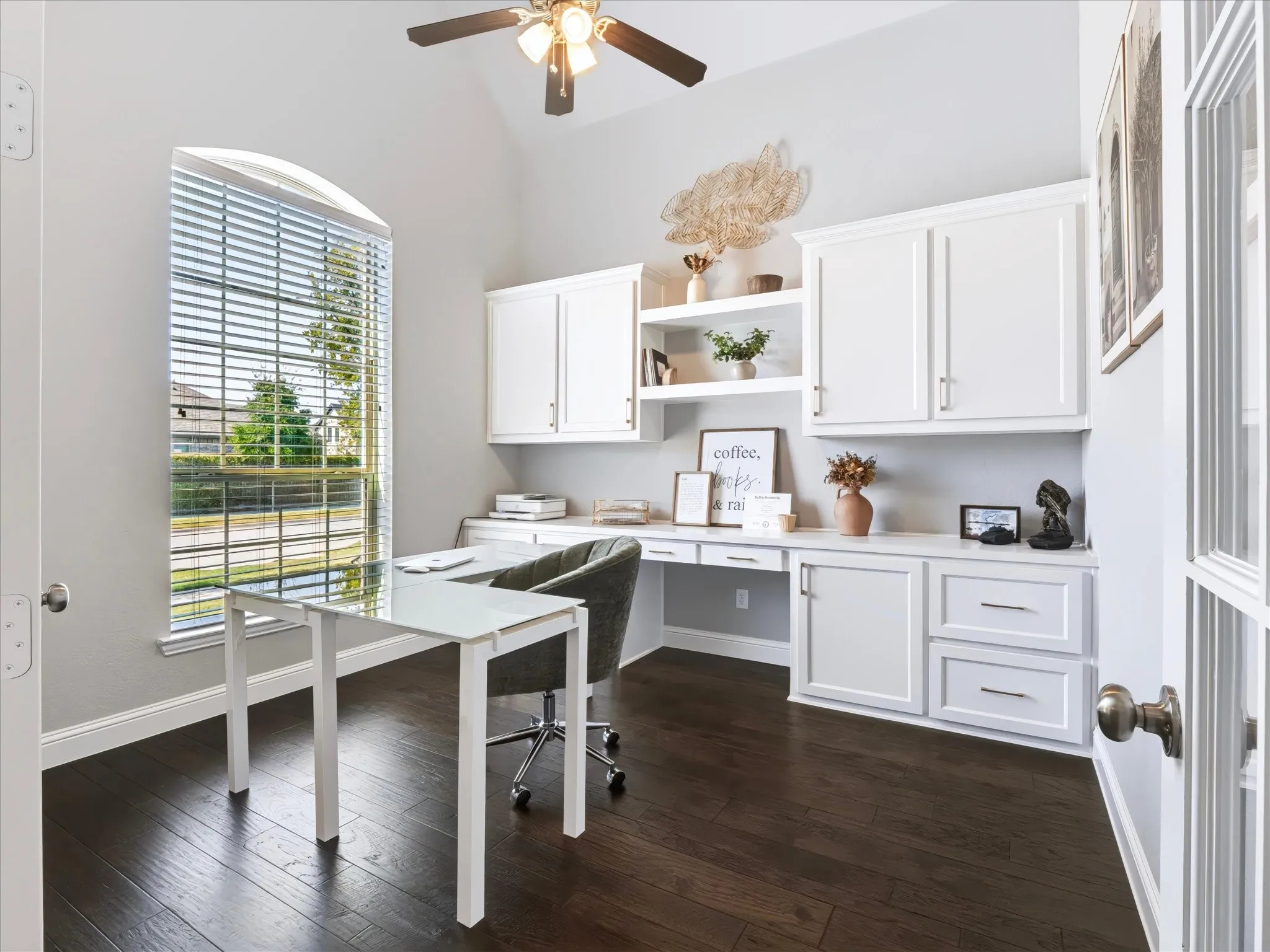 Vaulted ceiling with a ceiling fan, arched window, built-in cabinetry with a white countertop, and dark wood-finish flooring