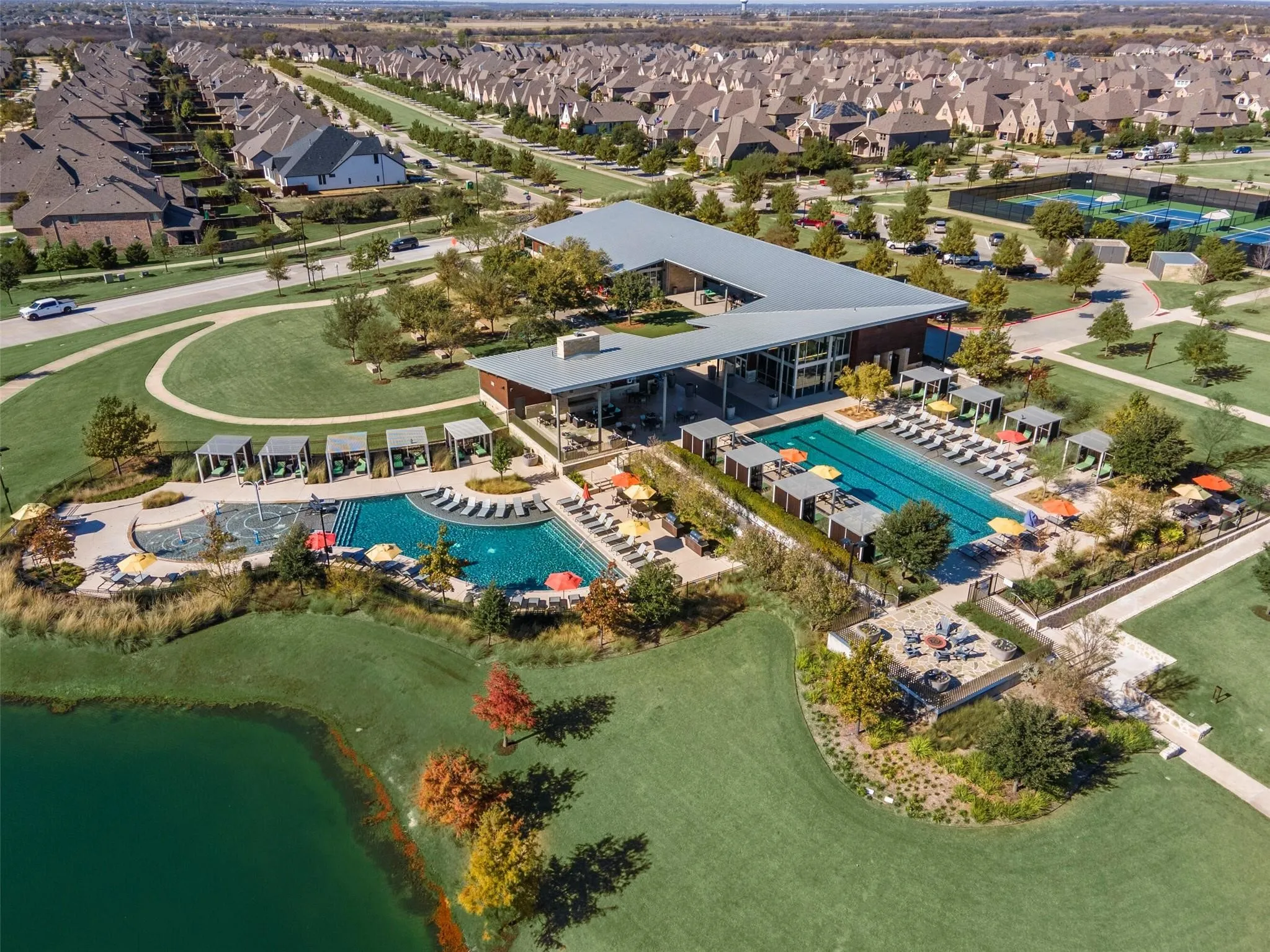 Community amenity center featuring a contemporary clubhouse, multiple swimming pools, and a separate aquatic play area