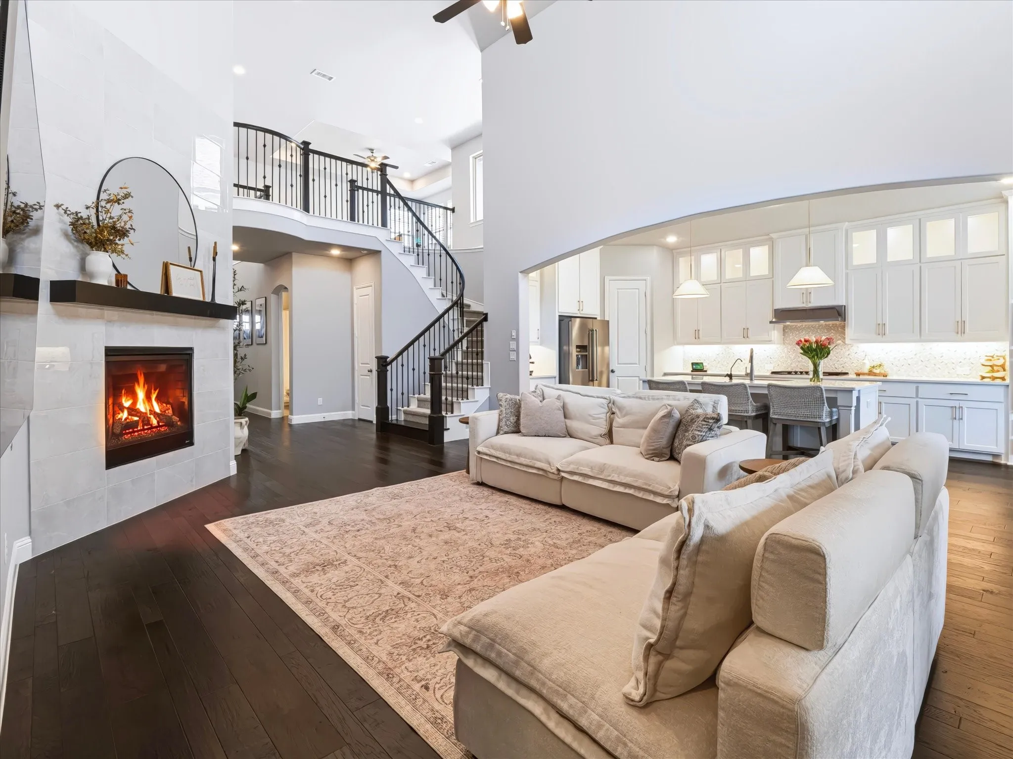 Two-story ceiling, dark wood-finish flooring, and upgraded tiled fireplace