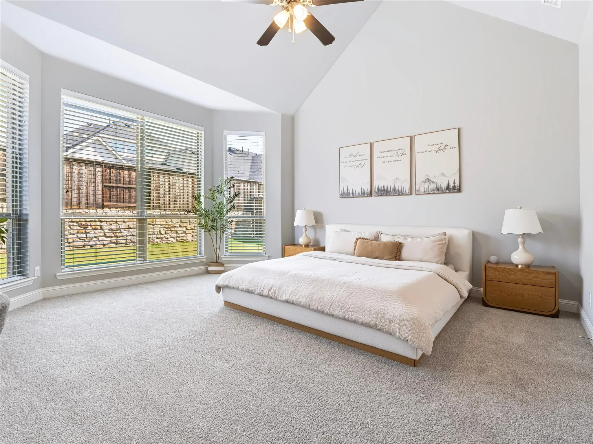 Vaulted ceiling with a ceiling fan, abundant natural light, light-toned carpeting, and a bay window
