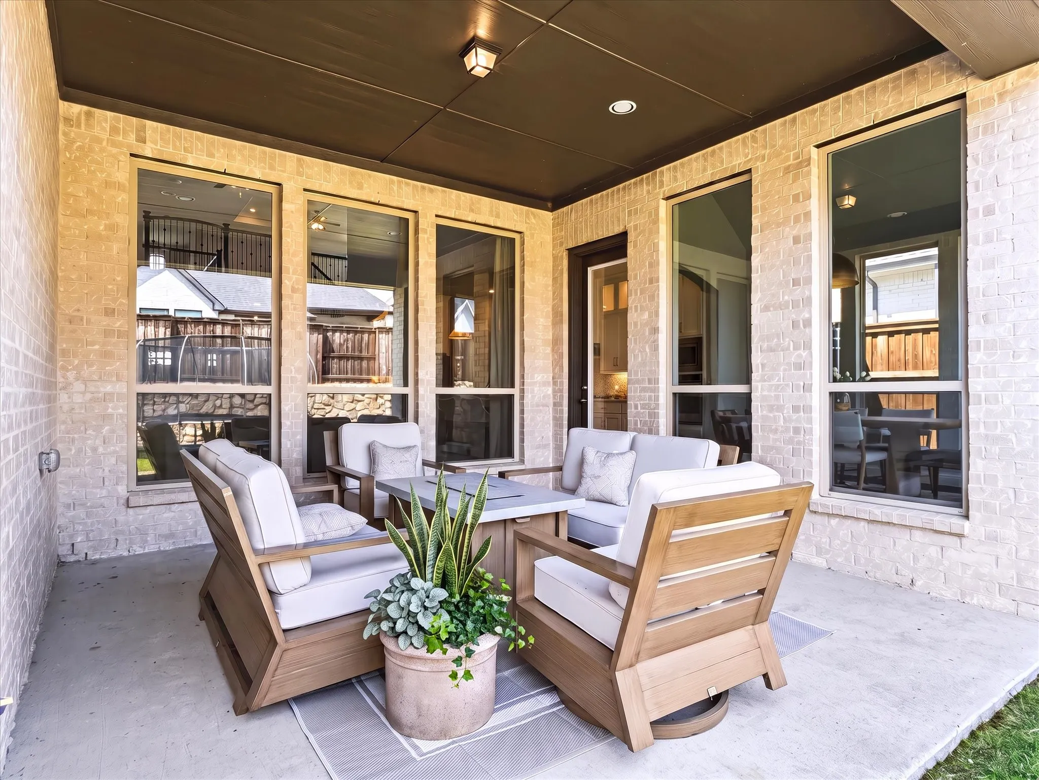 Covered patio with a concrete surface, brick wall, and dark soffit with recessed lighting