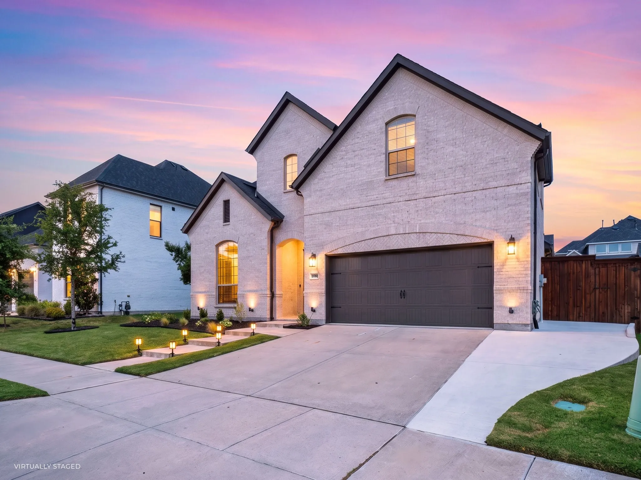 Stone veneer facade, dark trim accents, concrete driveway, arched garage door, and exterior sconce lighting