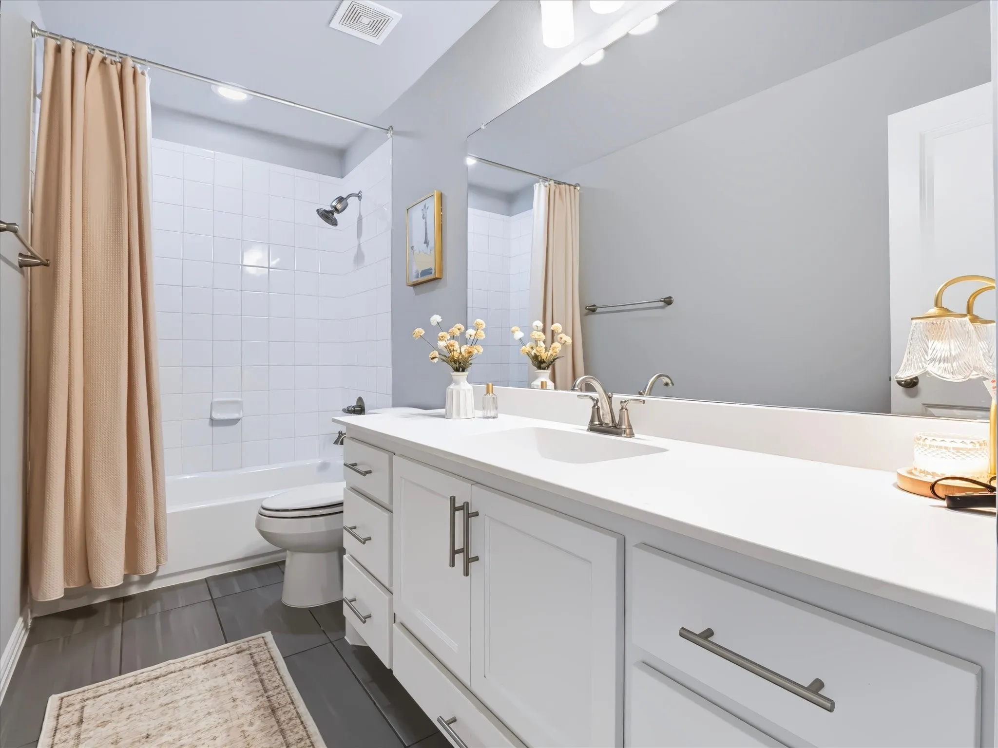 White vanity with ample storage, a single basin sink, and a large wall-mounted mirror