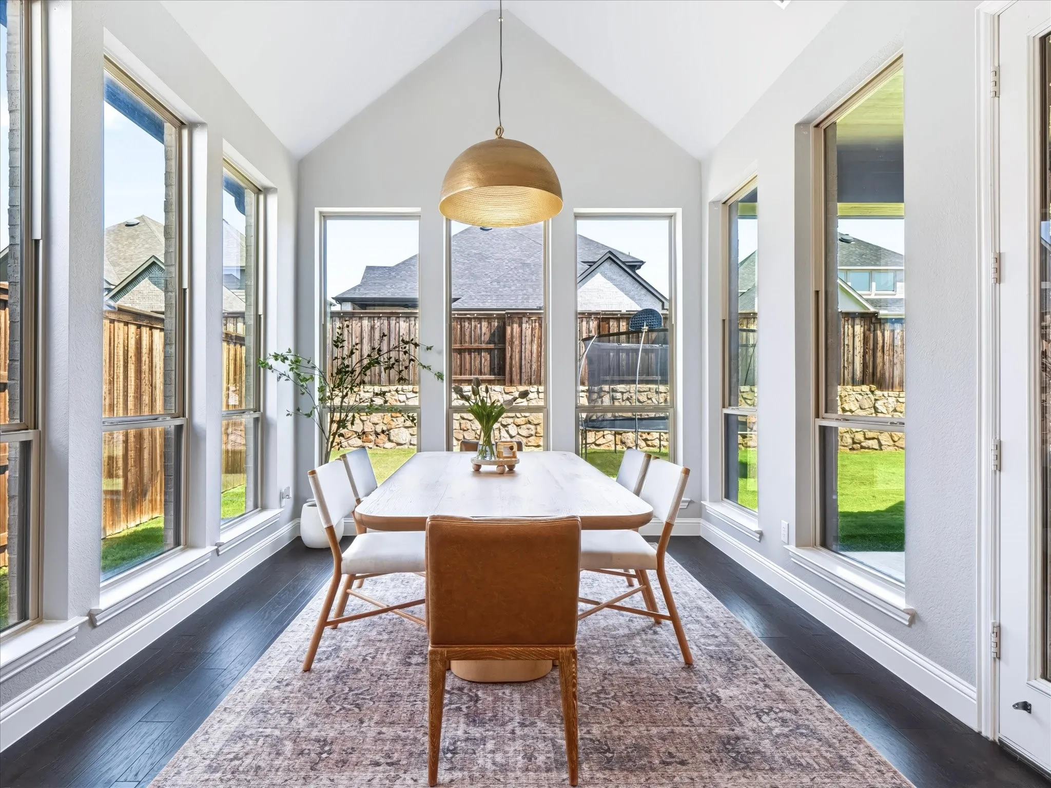 Vaulted ceiling, dark wood-finish flooring, multiple casement windows, and a built-in pendant light fixture