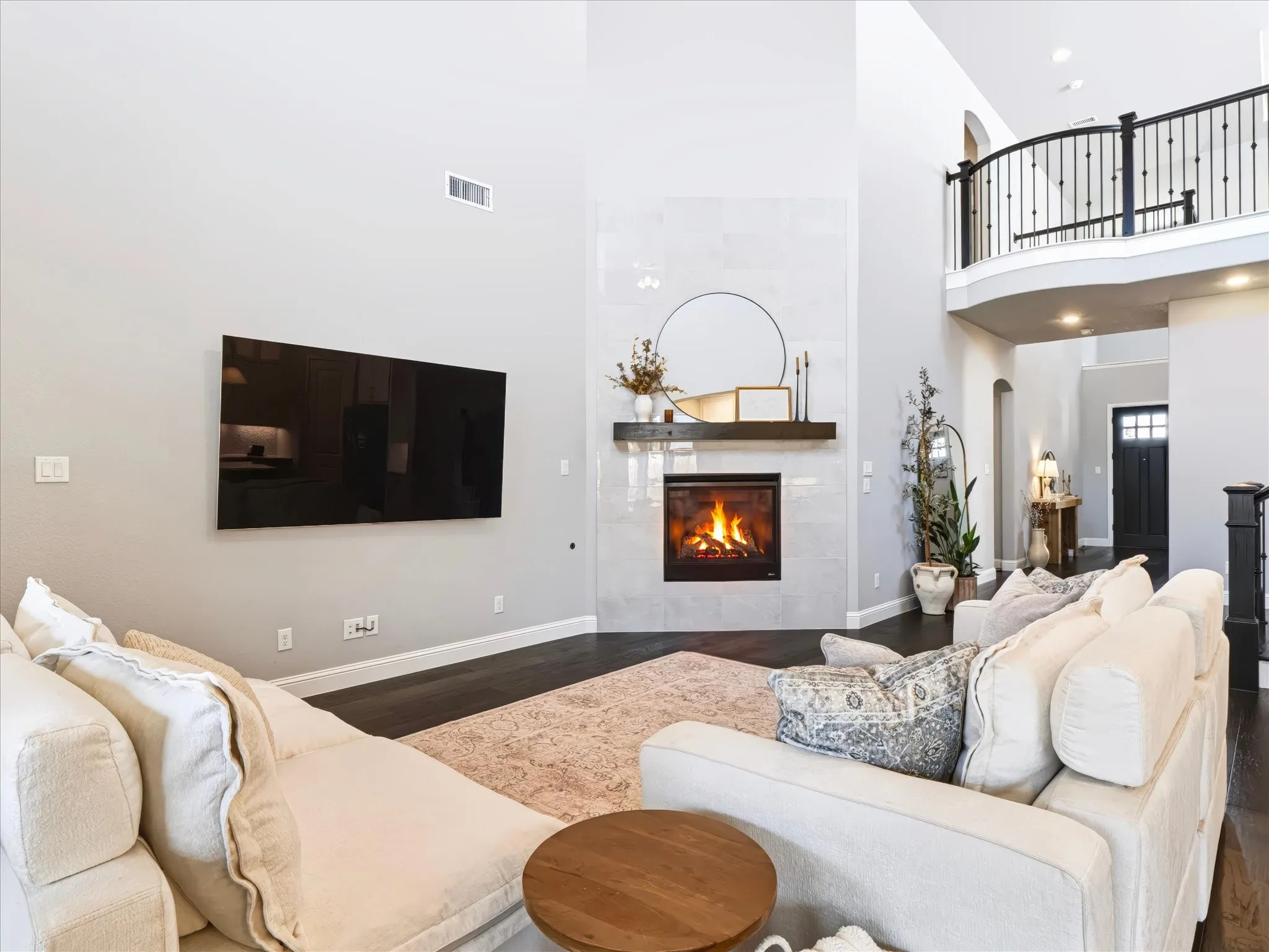 Two-story living area with a fireplace featuring a tile surround and a dark wood-finish mantel