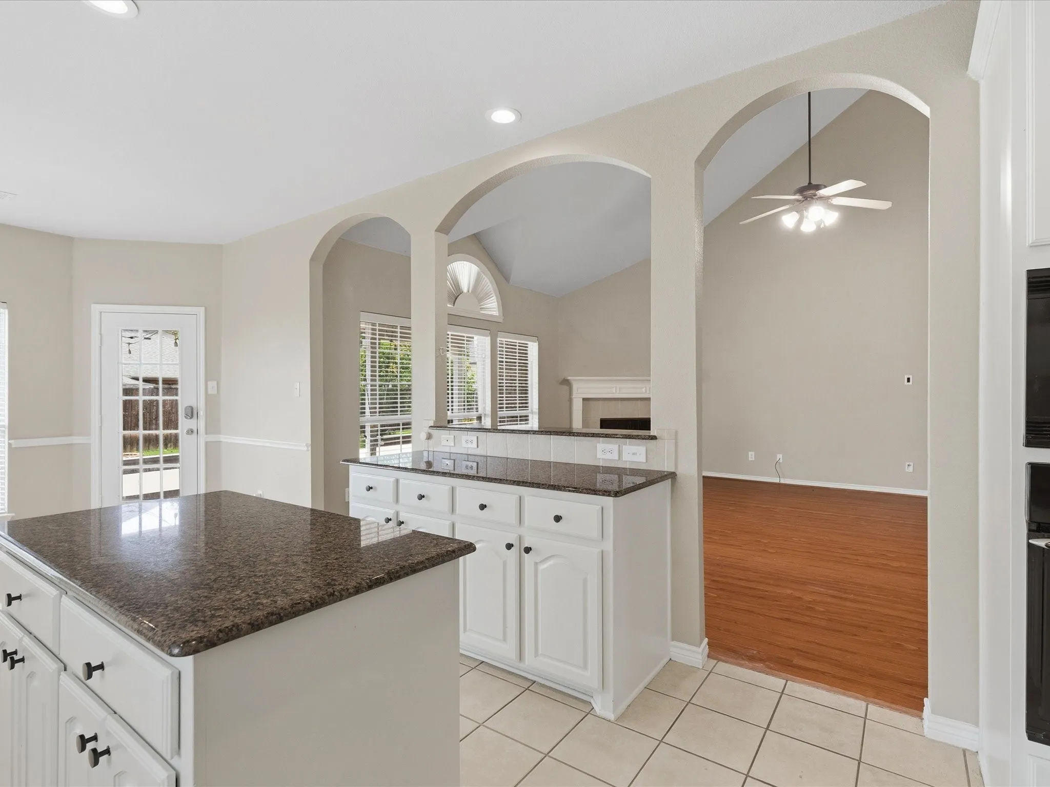 Kitchen island with dark speckled countertop and white cabinetry, recessed lighting, and tile flooring