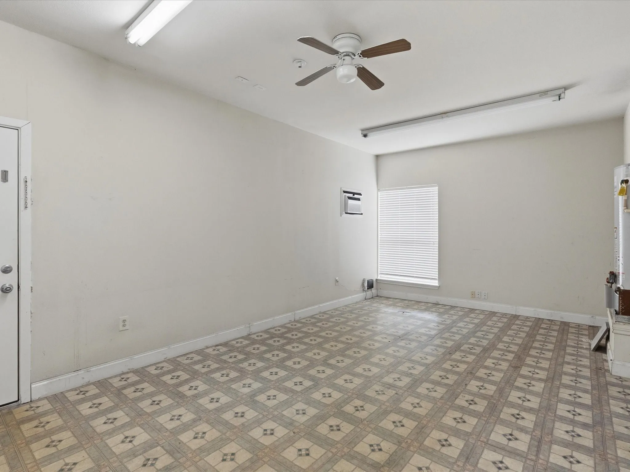 Spacious room featuring patterned linoleum flooring and light-toned walls