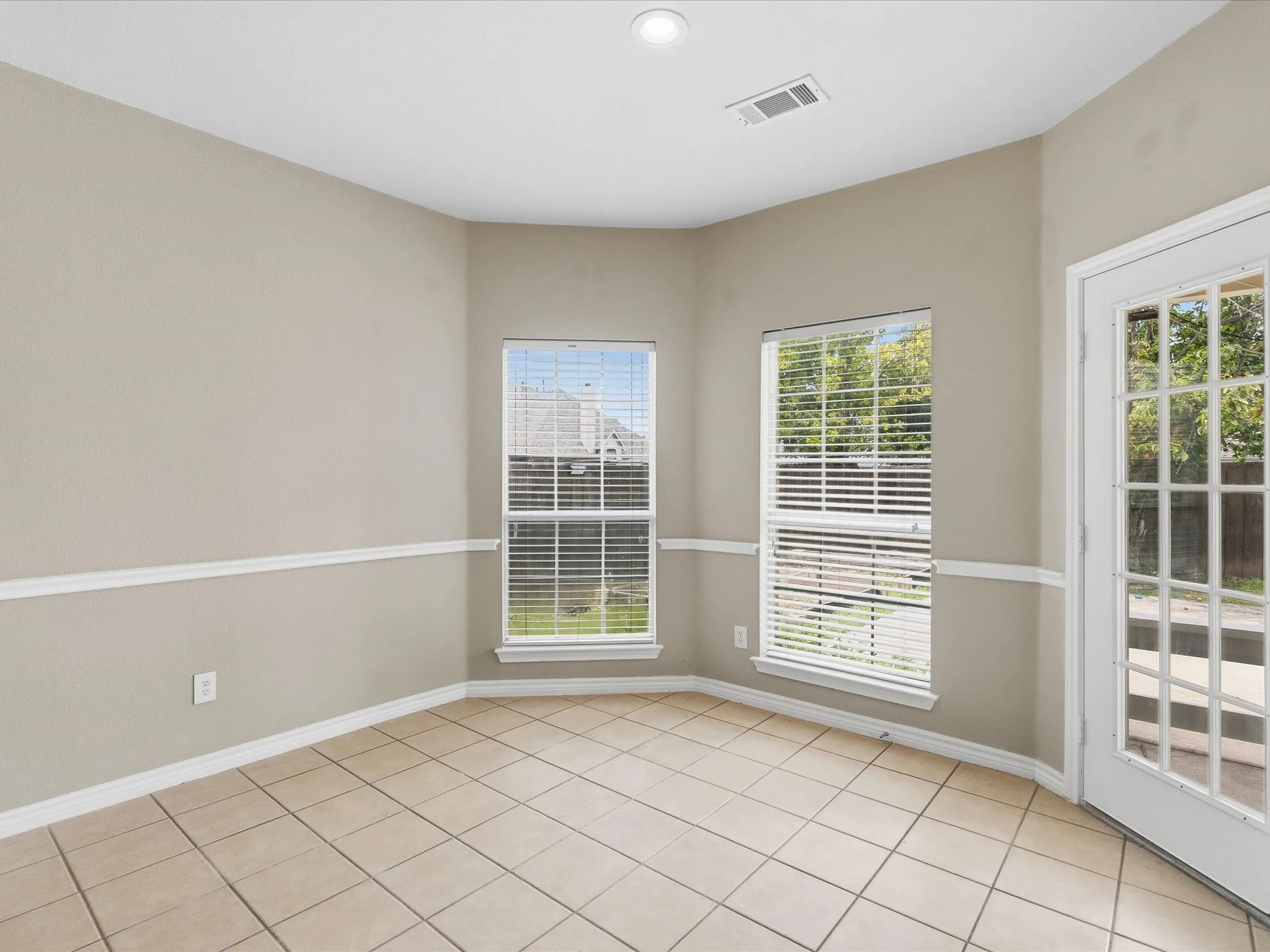 Bay window with two large windows, ceramic tile flooring, neutral wall tones, white trim, and a full-light glass door