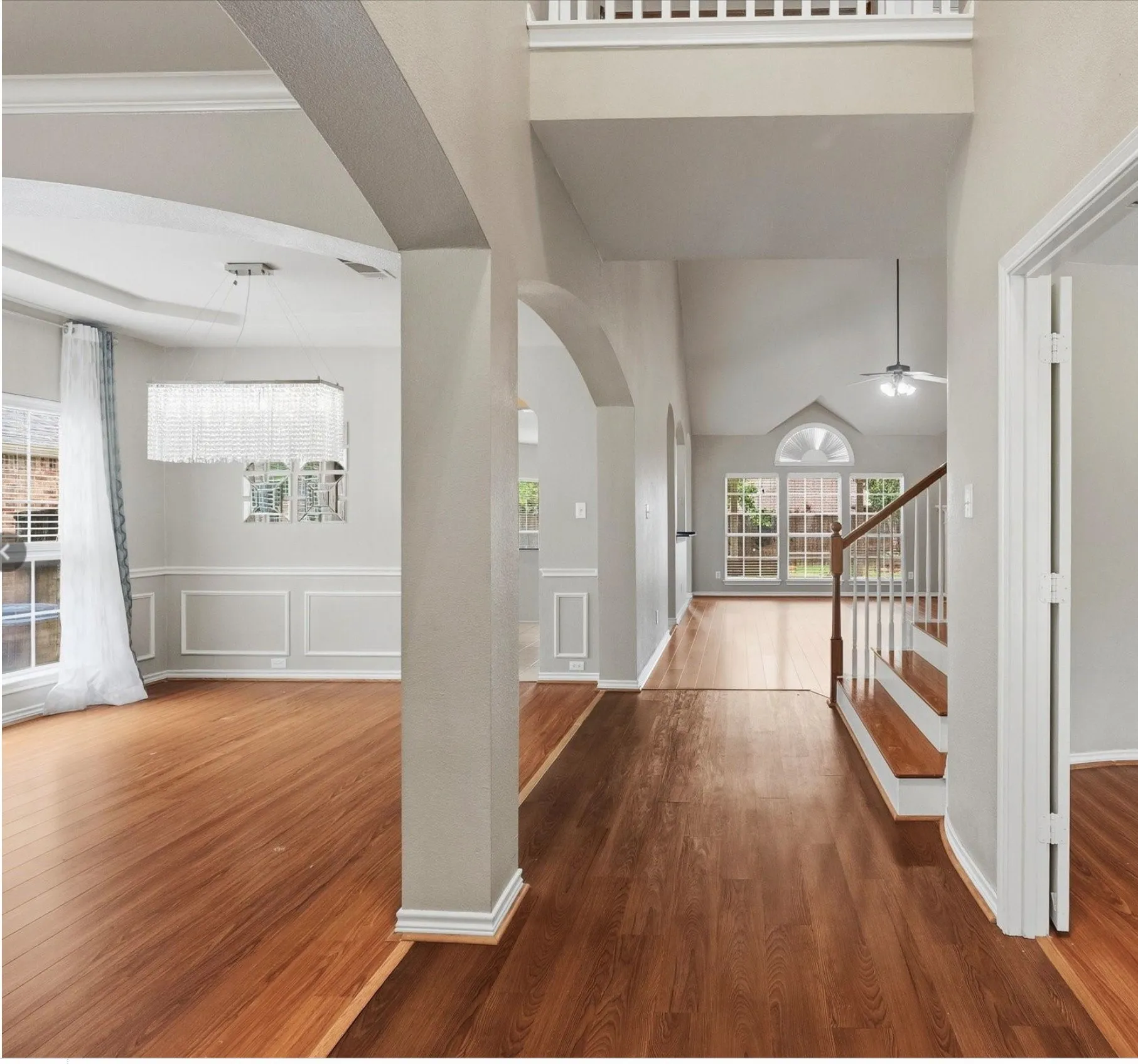 Entryway featuring wood-finish flooring, a grand staircase with white balusters, and a vaulted ceiling