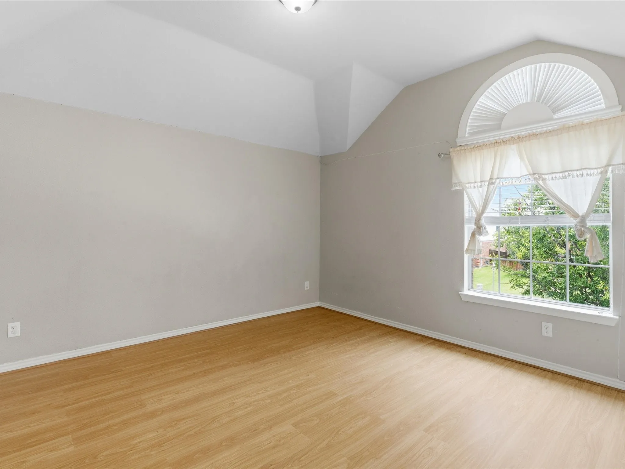 Room featuring a vaulted ceiling and wood-finish flooring