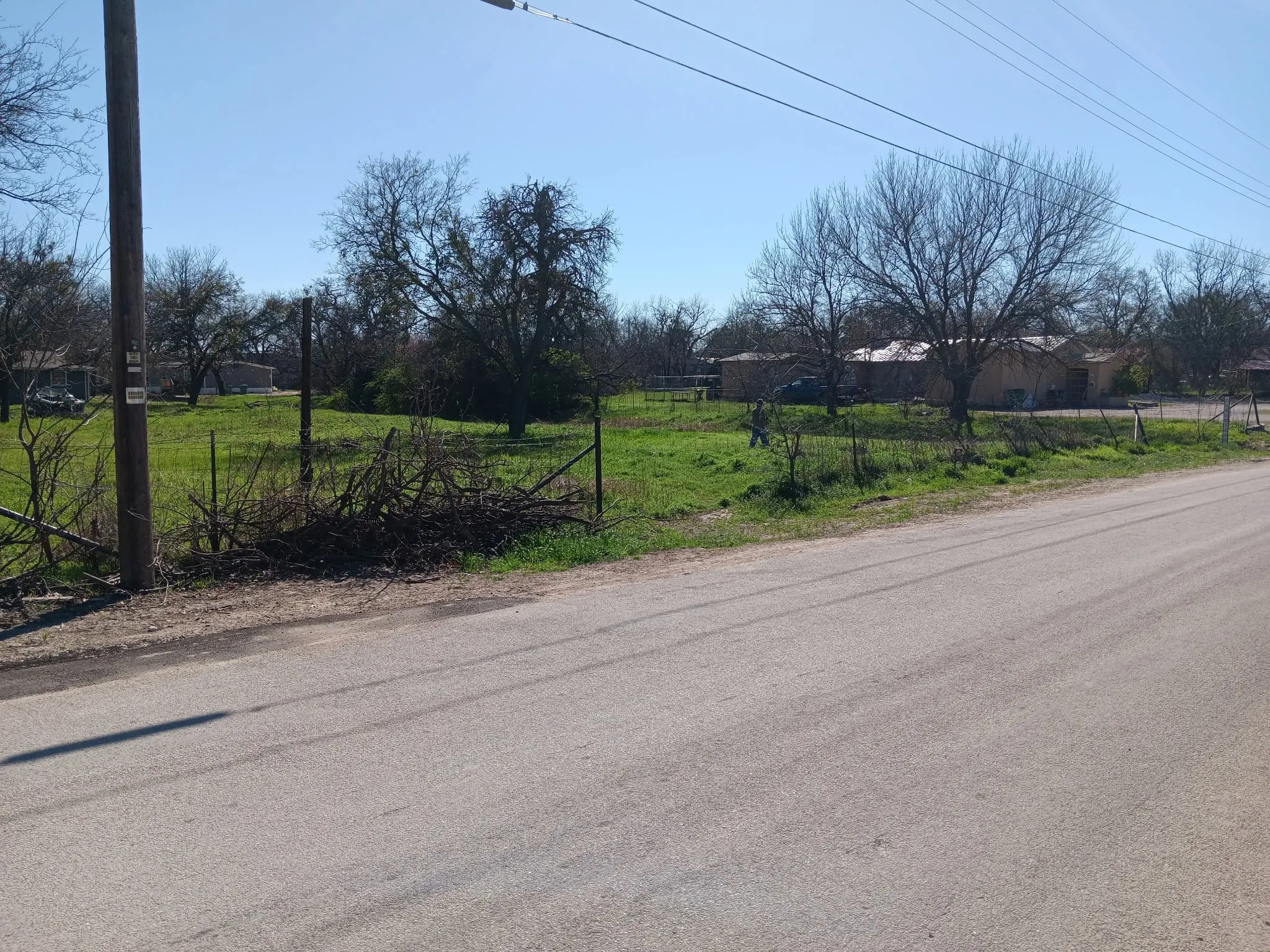 Expansive grassy lot featuring mature trees and partial fencing