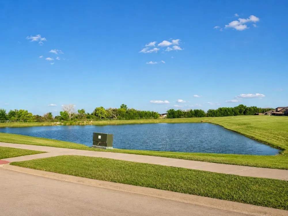 Expansive waterfront property featuring a large pond and surrounding green space