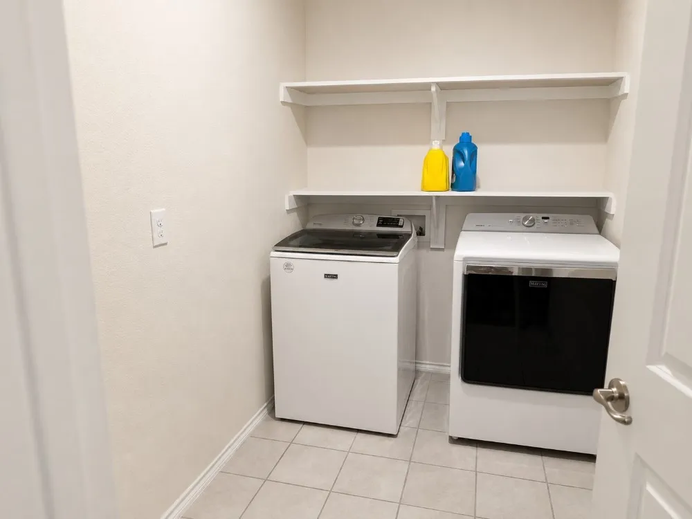 Dedicated utility space featuring tile flooring and neutral wall tones