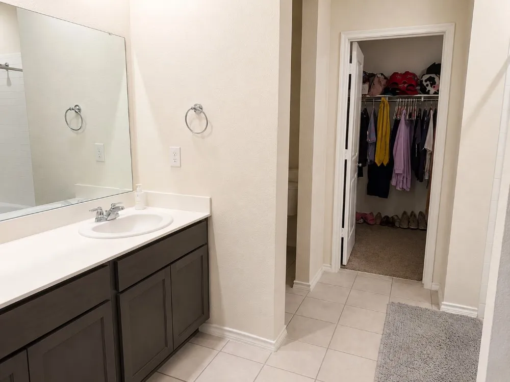Bathroom vanity featuring a single basin sink, chrome faucet, and expansive countertop