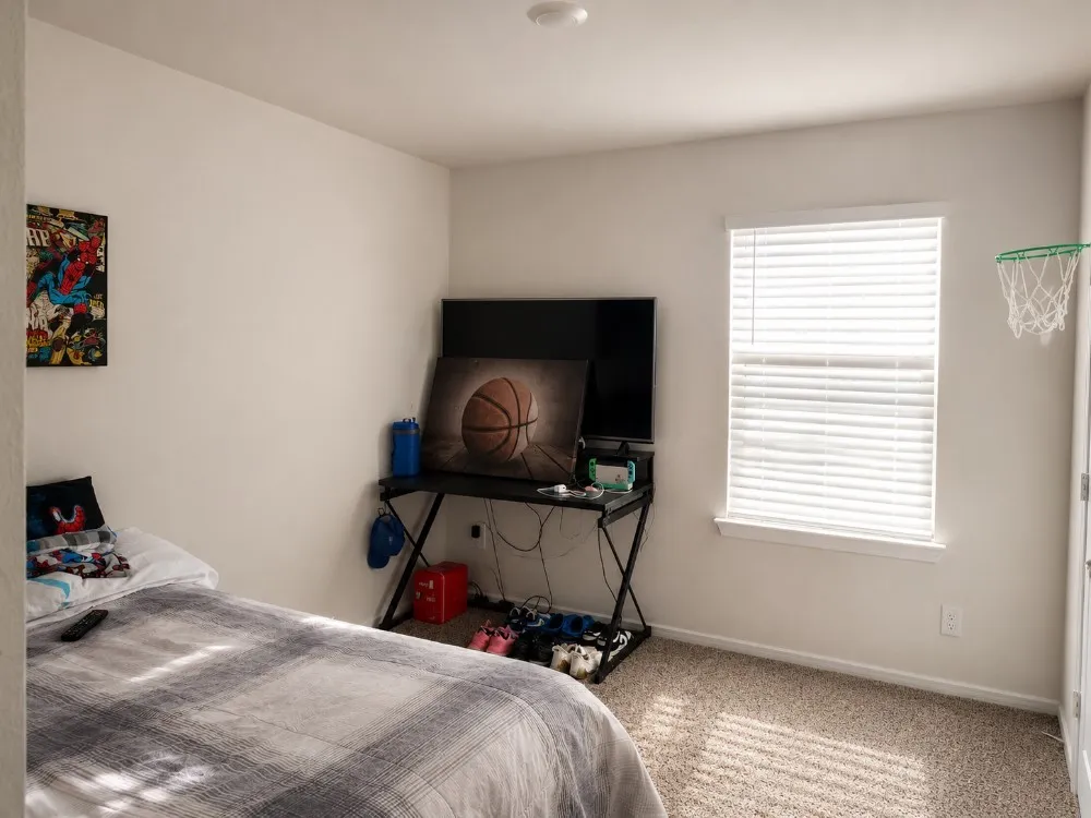 Carpeted room with a single window featuring white horizontal blinds, white walls, and a recessed ceiling light fixture