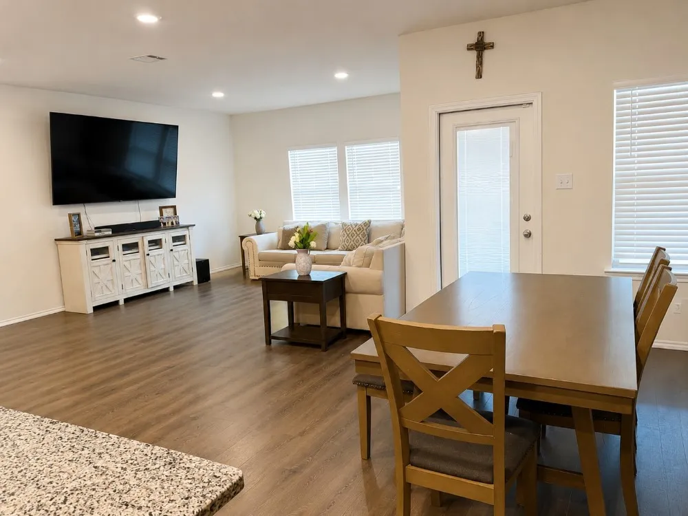 Open-concept living area with wood-finish flooring, recessed lighting, white walls, and multiple windows with horizontal blinds