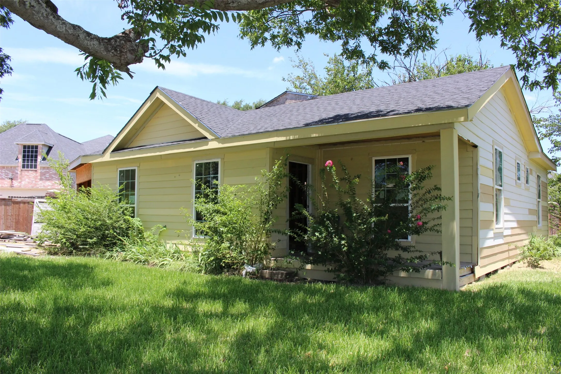 Single-story residence featuring light yellow siding and a dark shingle roof