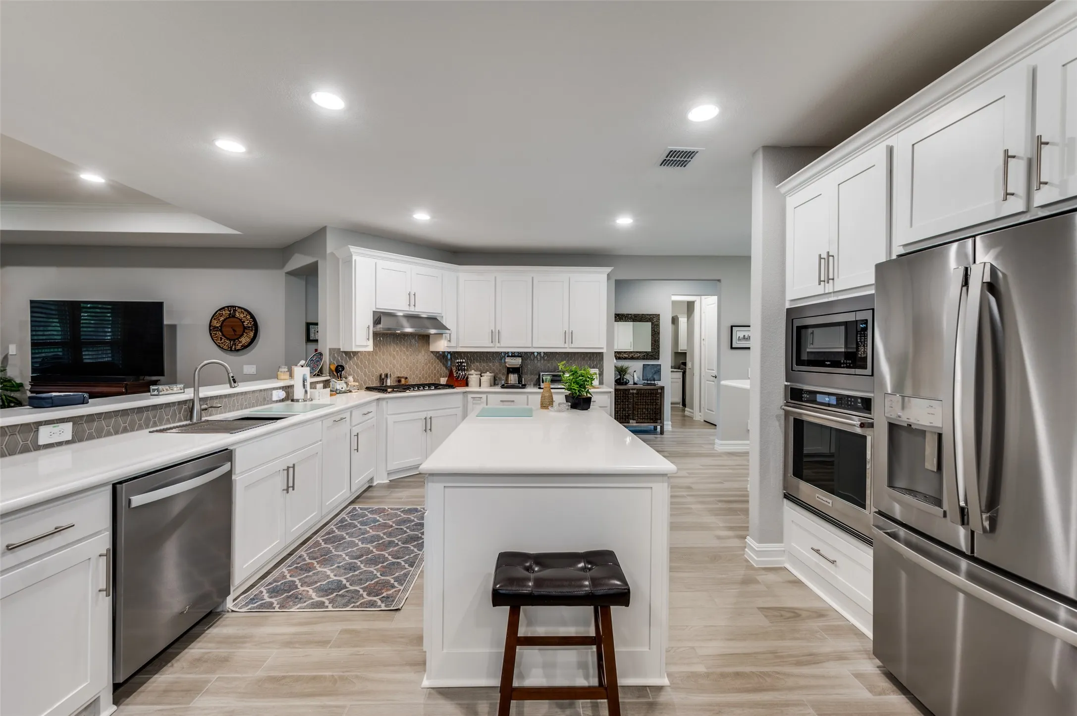 Kitchen featuring white cabinetry, stainless steel appliances, a center island with countertop, recessed lighting, and wood-finish flooring