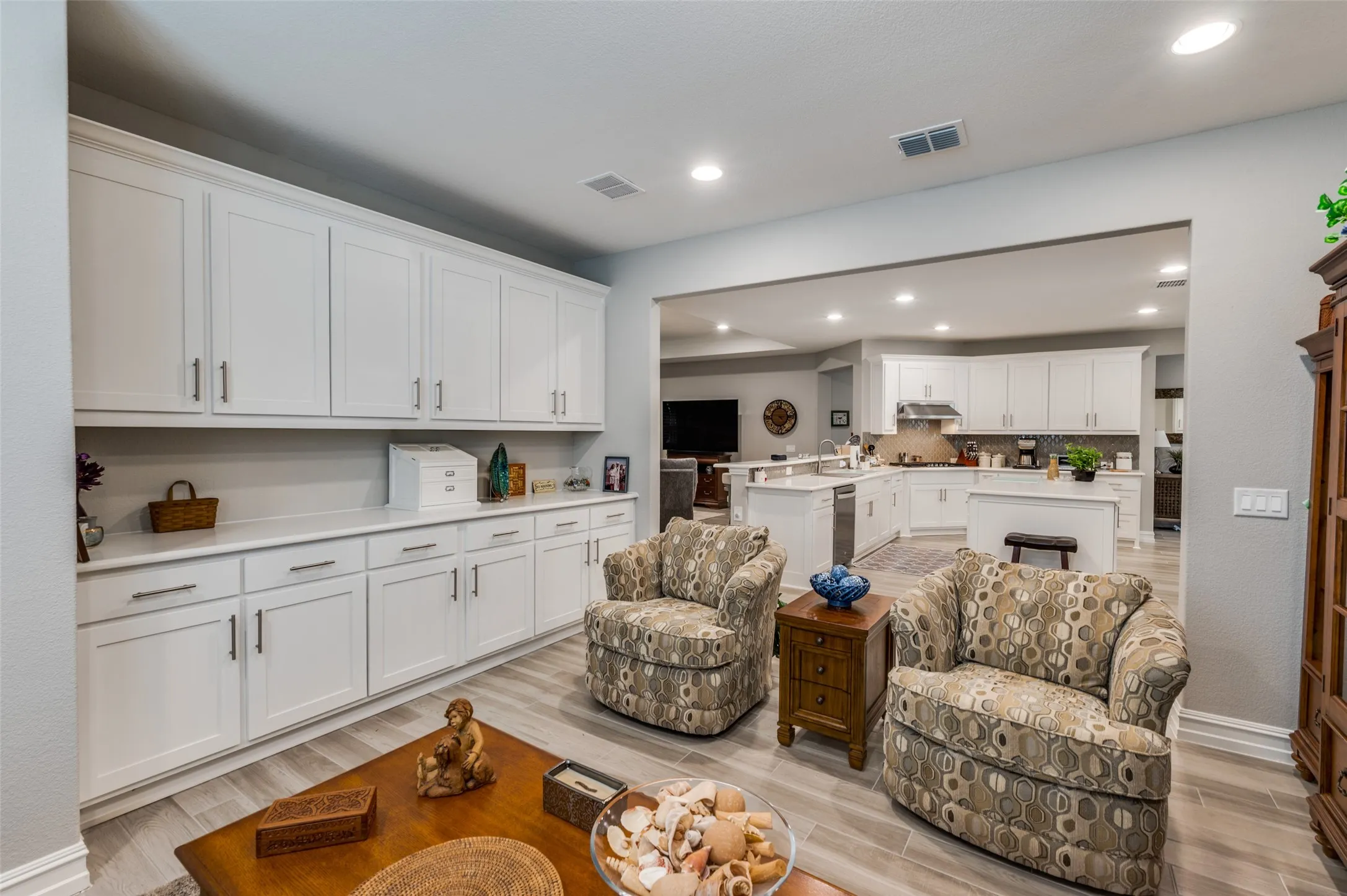 Spacious room featuring extensive white cabinetry with brushed nickel hardware, light-toned wood-finish flooring, and recessed lighting