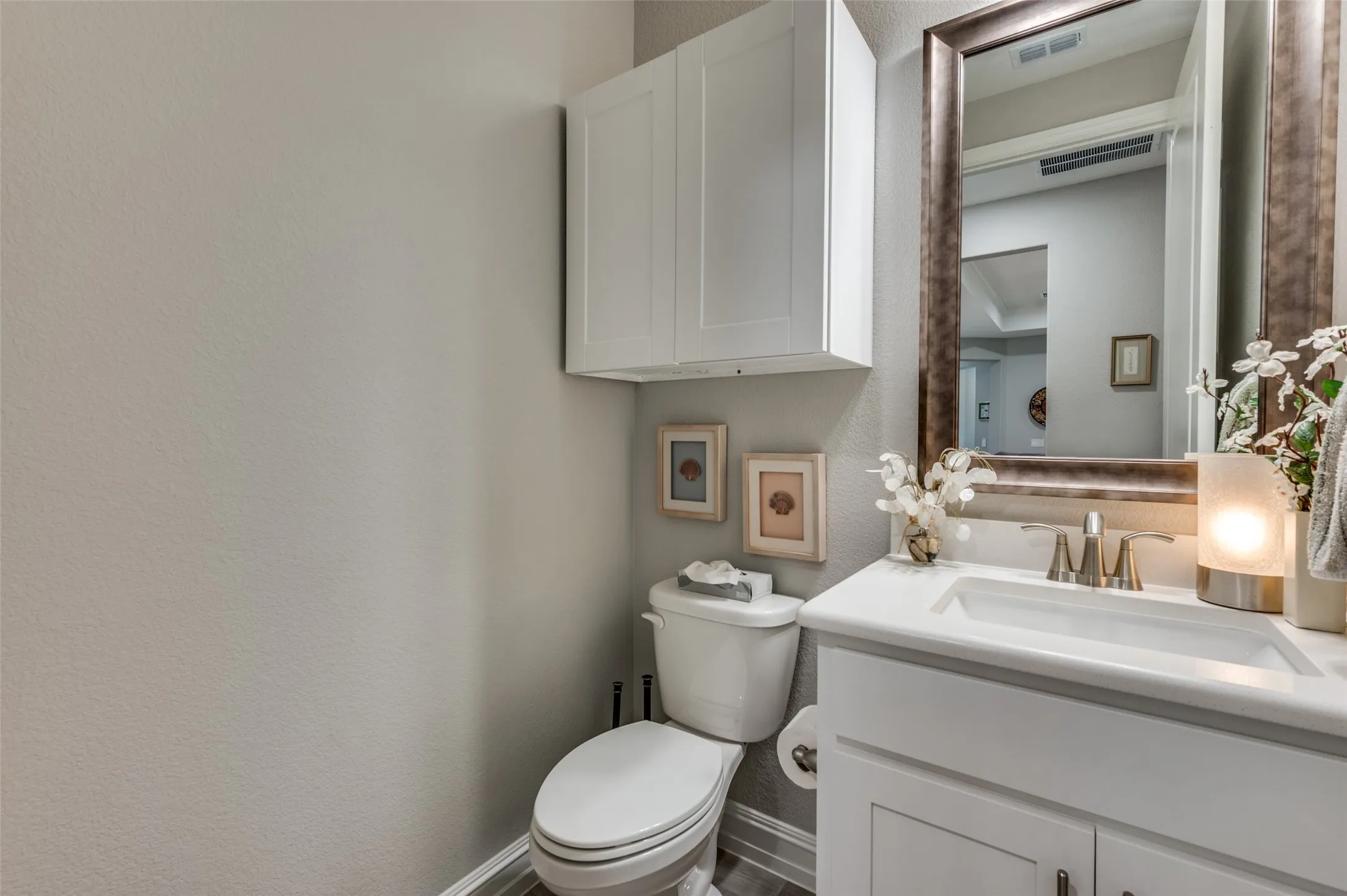 Bathroom vanity featuring a white rectangular sink, brushed nickel faucet, and a large framed mirror