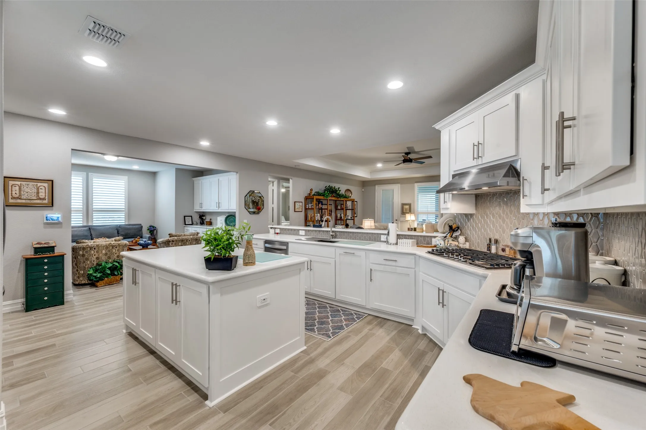 Open concept kitchen featuring white cabinetry, light-toned wood-finish flooring, recessed lighting, a kitchen island, and stainless steel appliances
