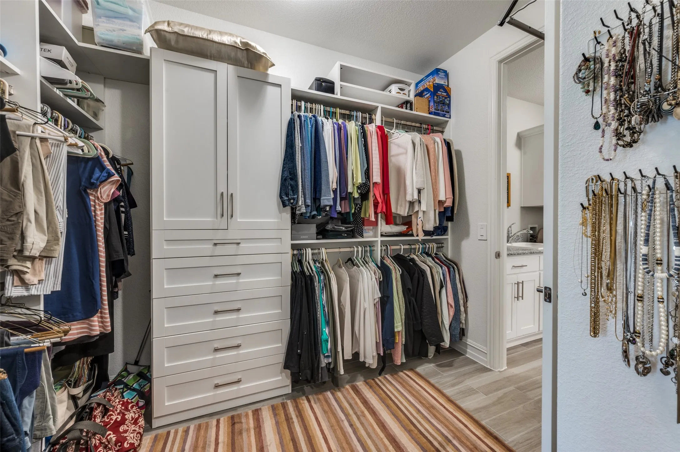 Custom closet system featuring built-in cabinetry, multiple hanging rods, and integrated shelving