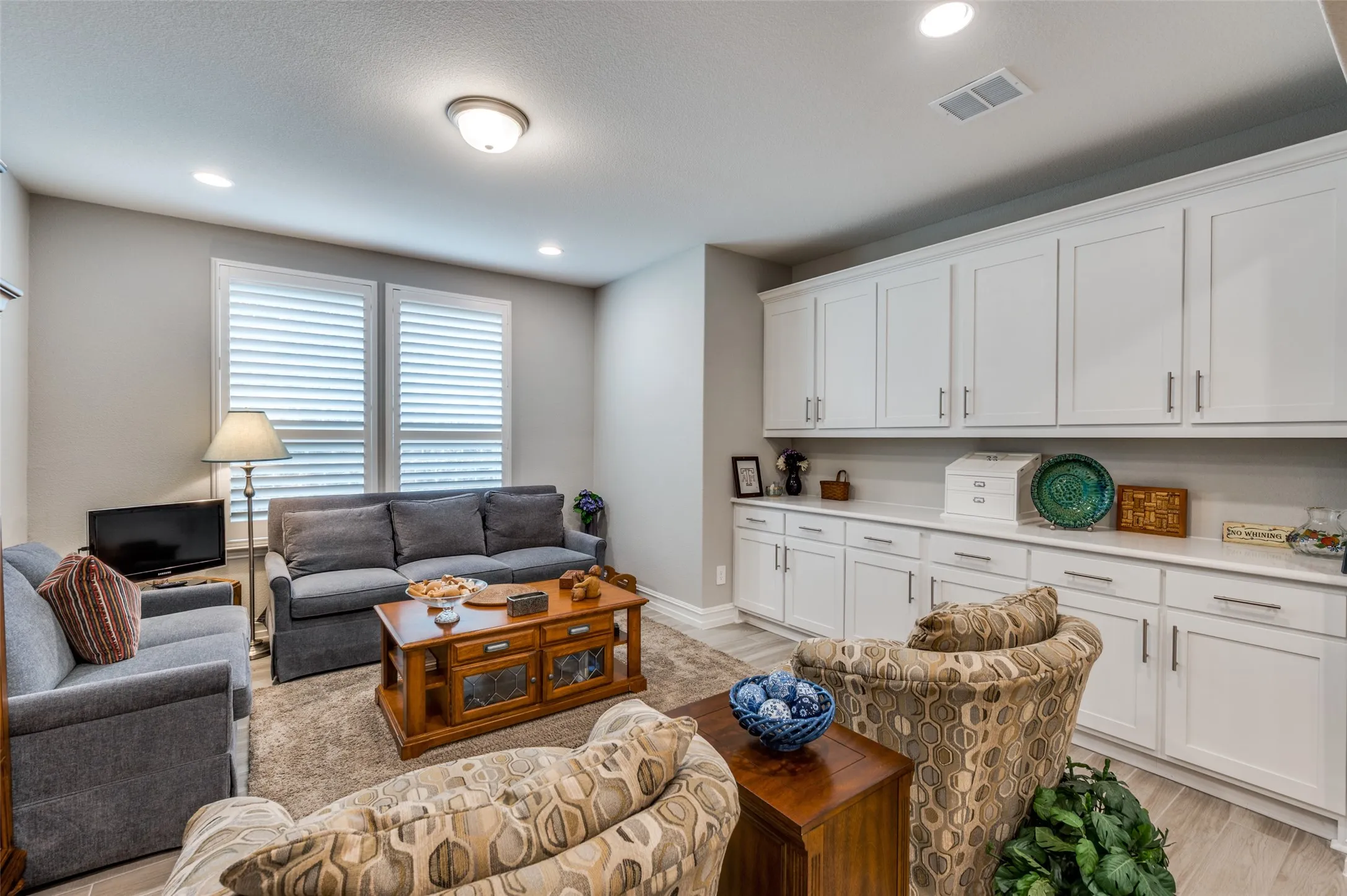 Dedicated storage room featuring extensive white cabinetry with brushed nickel hardware, light-toned countertops, and recessed lighting