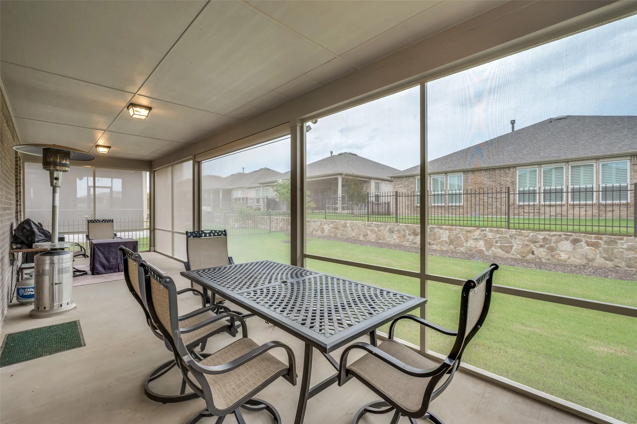 Screened porch featuring a concrete floor, brick exterior wall, and multiple ceiling-mounted light fixtures