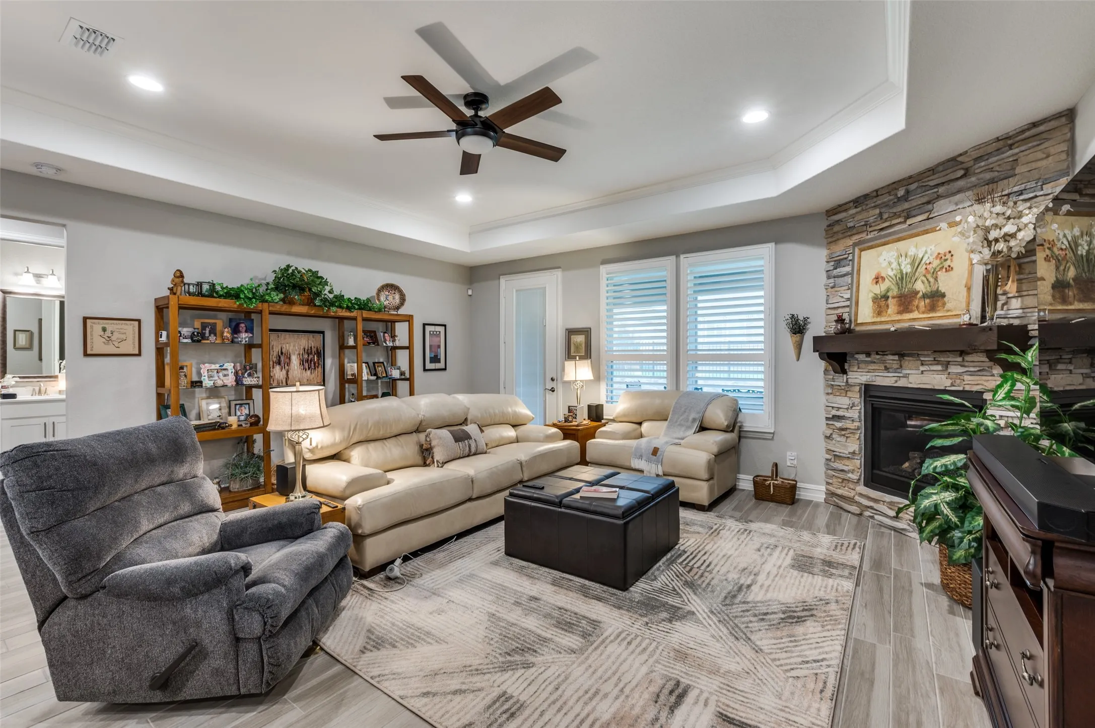 Living space featuring wood-look flooring, a tray ceiling with a ceiling fan, and recessed lighting