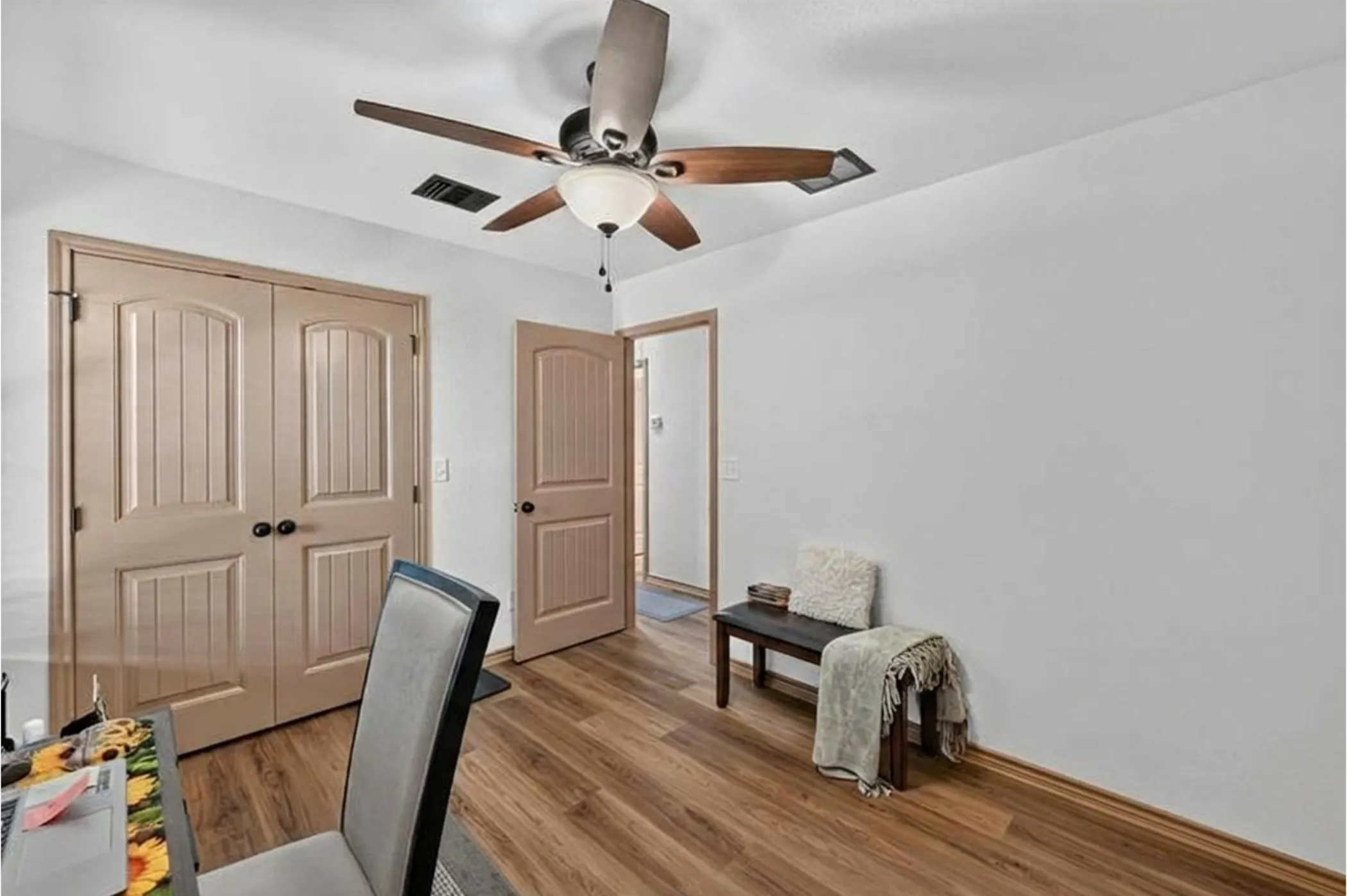 Wood-finish flooring throughout, featuring light-colored walls and a ceiling fan