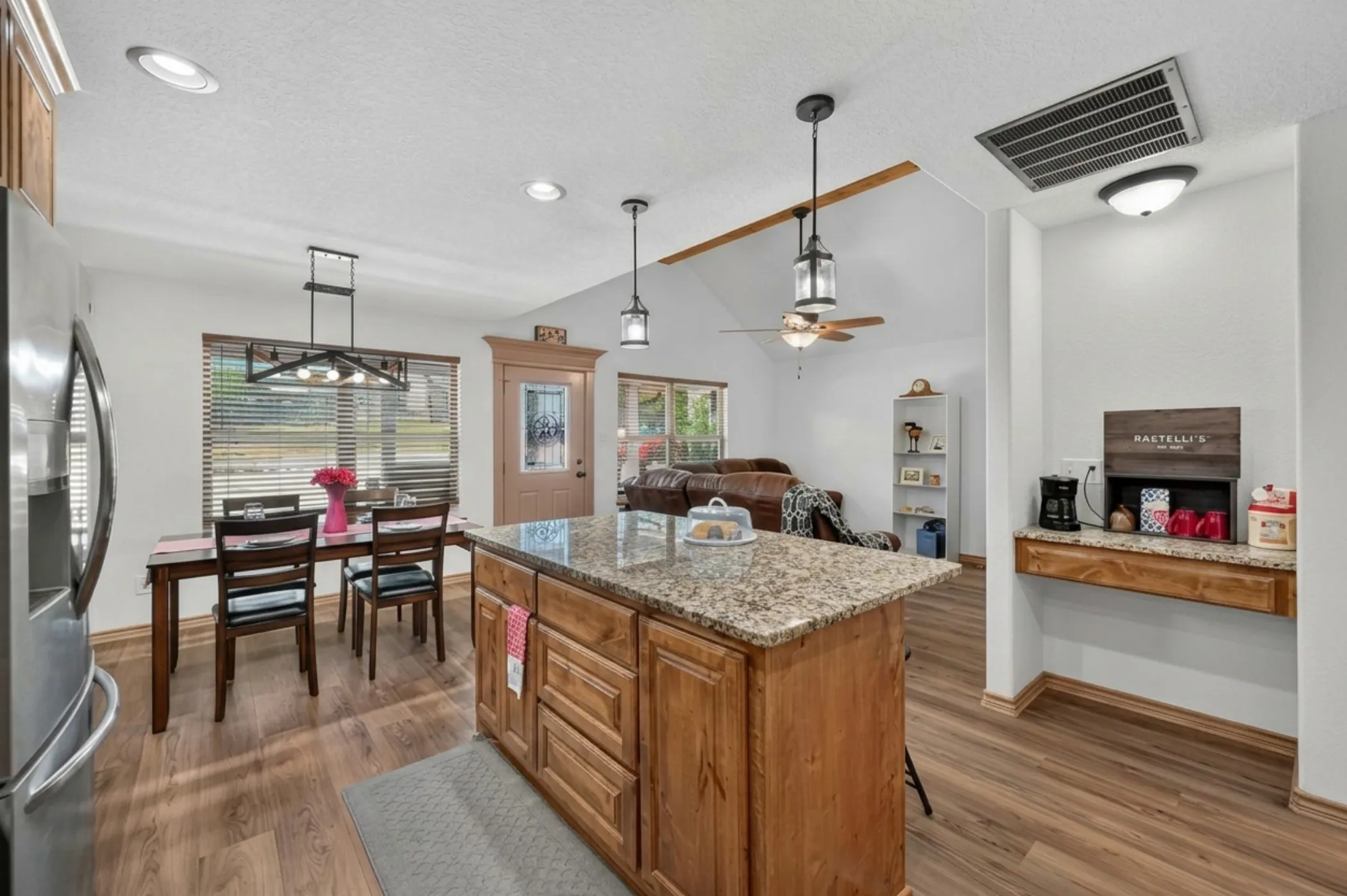 Spacious kitchen featuring a central island with granite countertop and wood cabinetry, wood-finish flooring, recessed lighting, and a dedicated coffee bar area