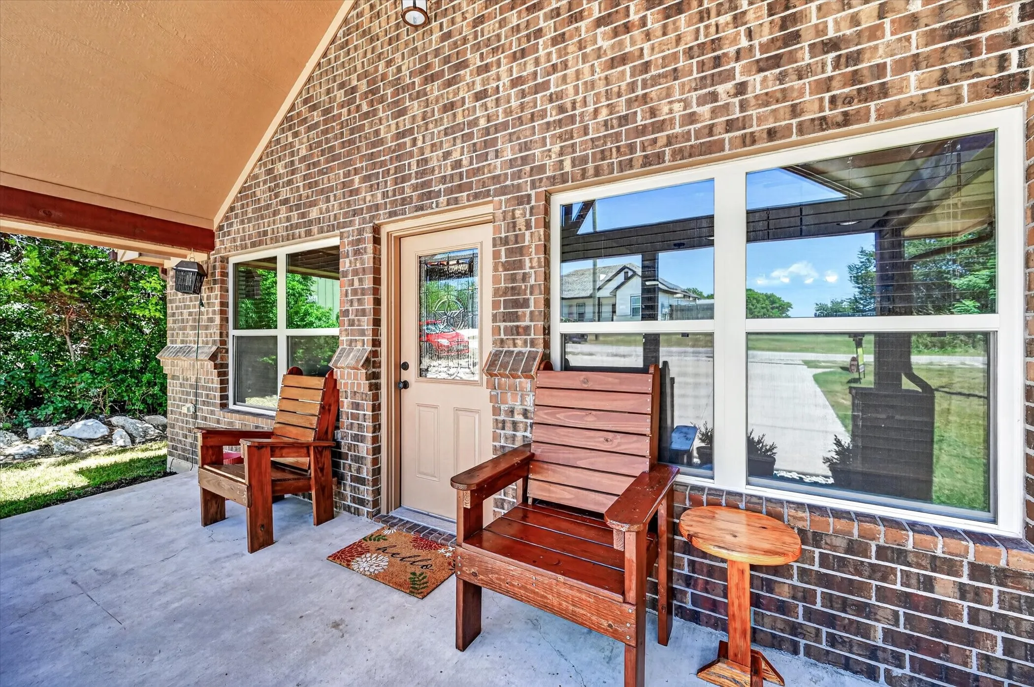 Covered front porch featuring brick exterior, a paneled entry door with frosted glass, and multi-pane windows