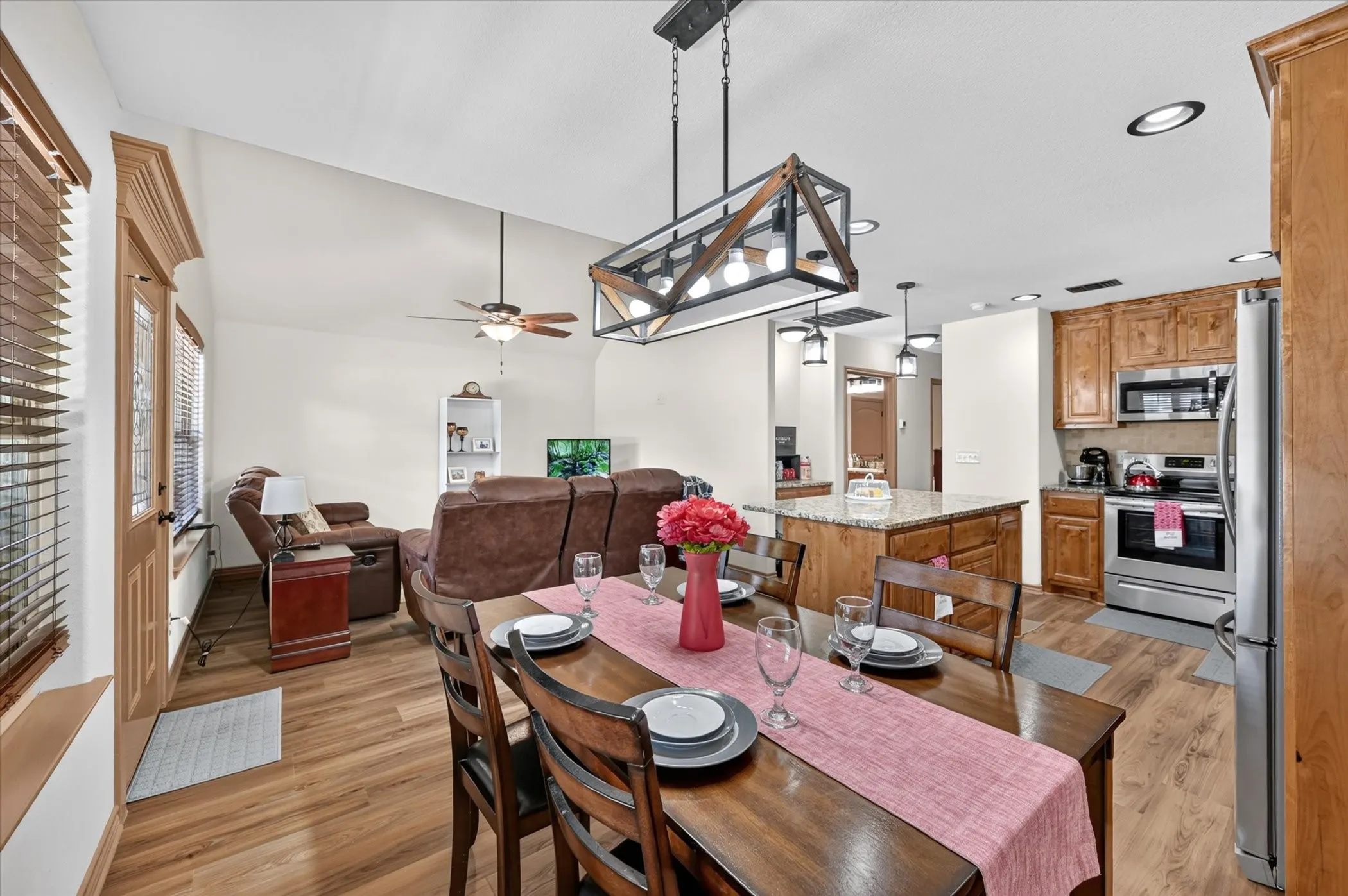 Open-concept living area featuring wood-finish flooring, vaulted ceilings, and a modern linear chandelier