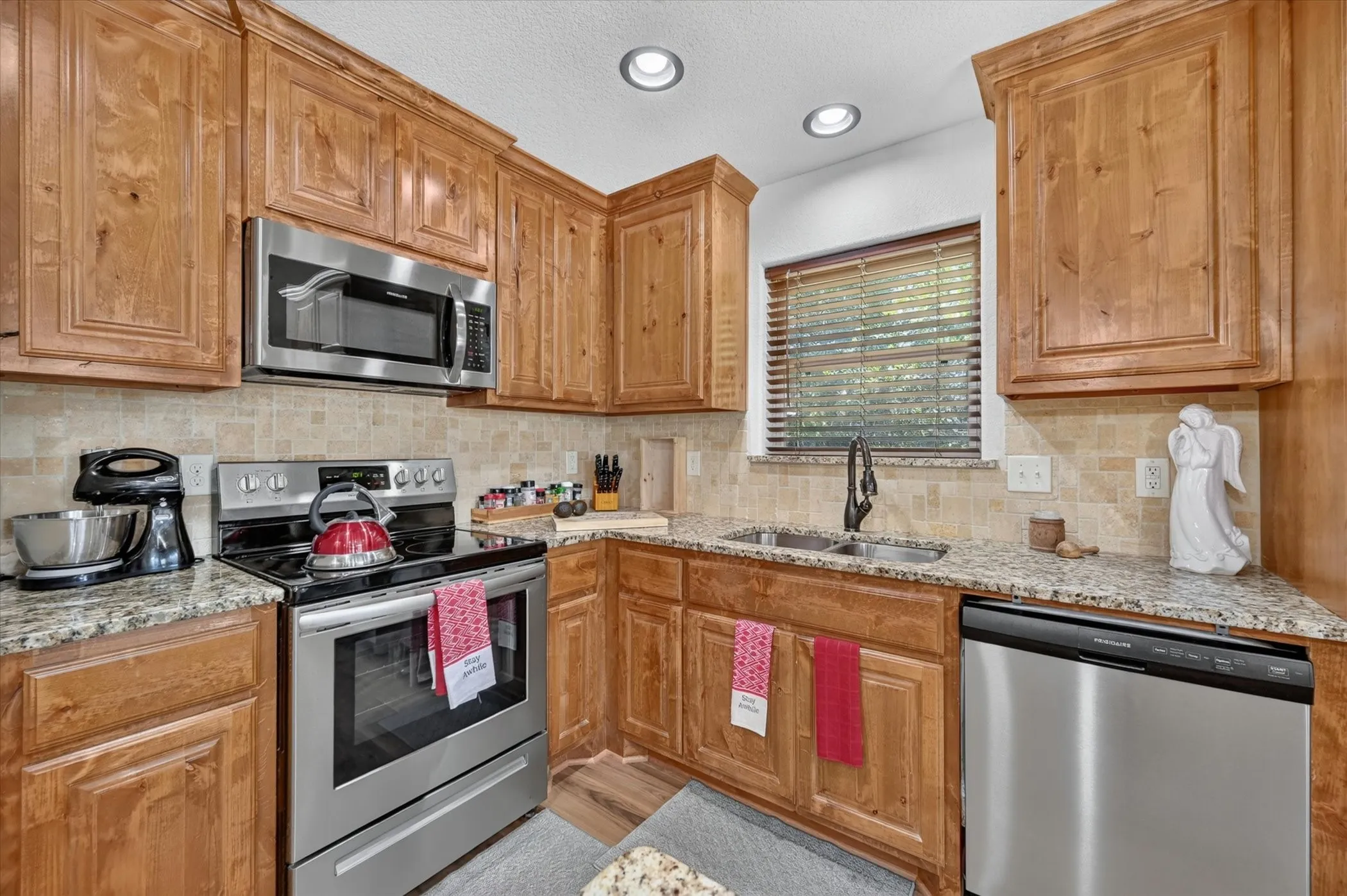Kitchen featuring wood cabinetry, stainless steel appliances, speckled countertops, and a tiled backsplash