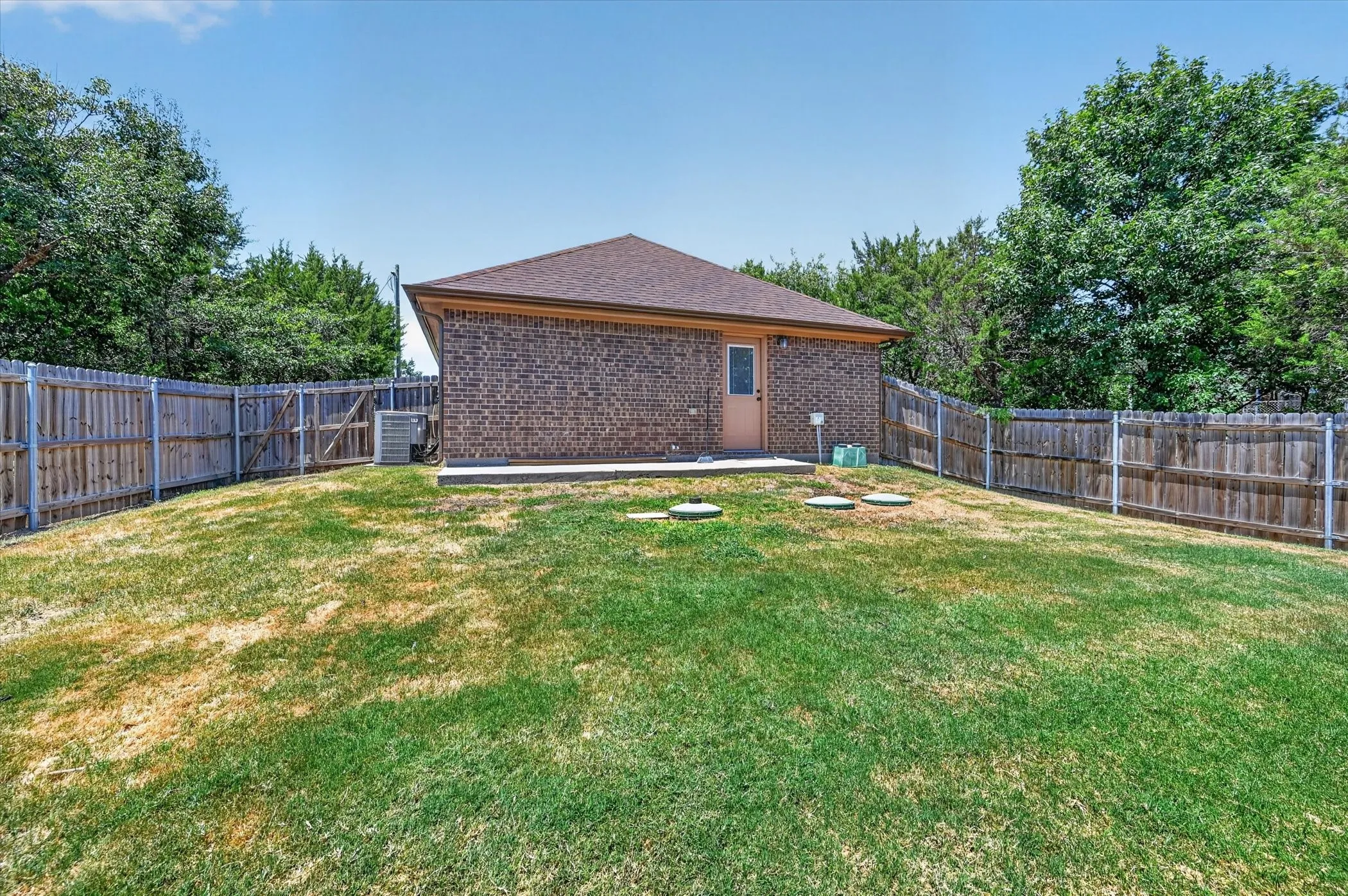 Expansive backyard featuring a brick exterior structure with a brown shingle roof