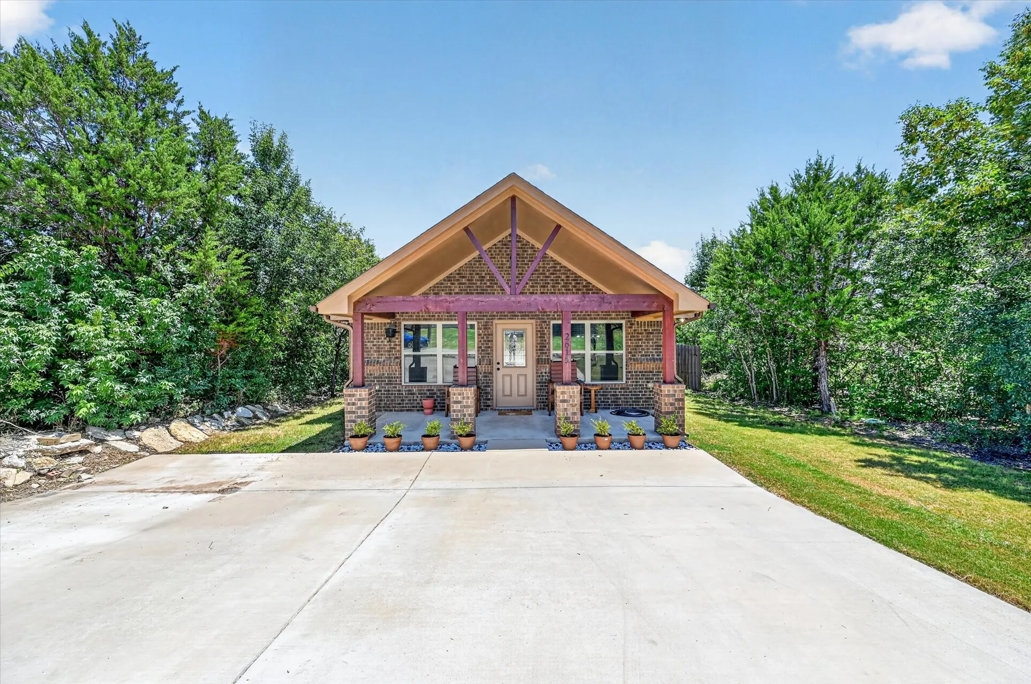 Brick facade home featuring a covered front porch with exposed timber framing and columns