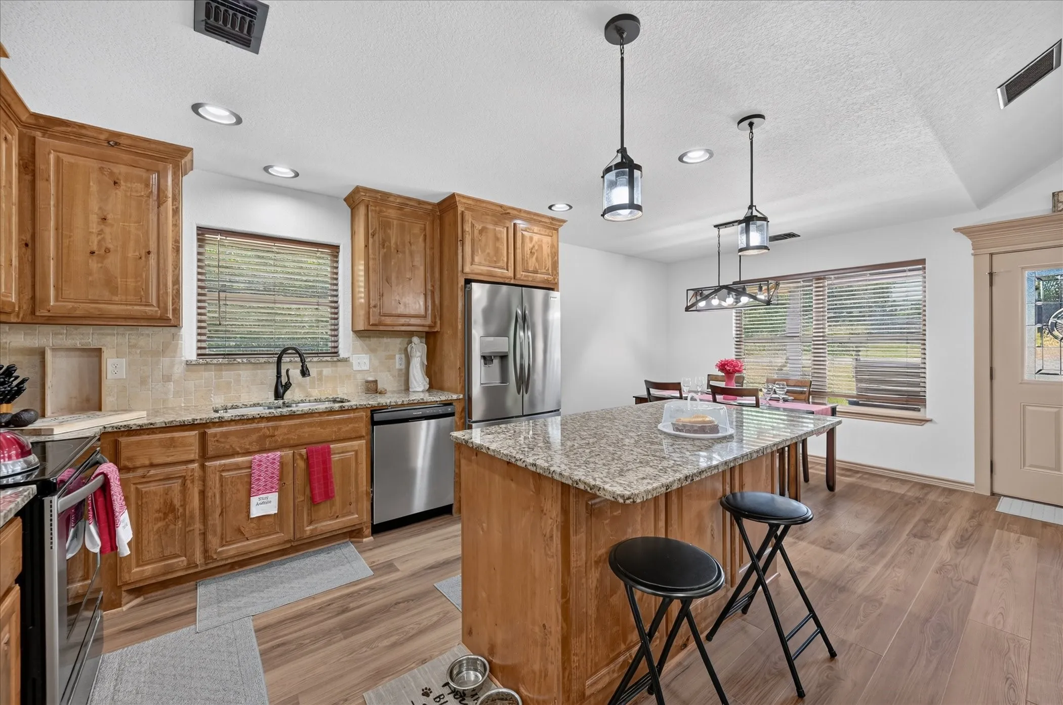 Kitchen featuring wood cabinetry, granite countertops, stainless steel appliances, and wood-finish flooring