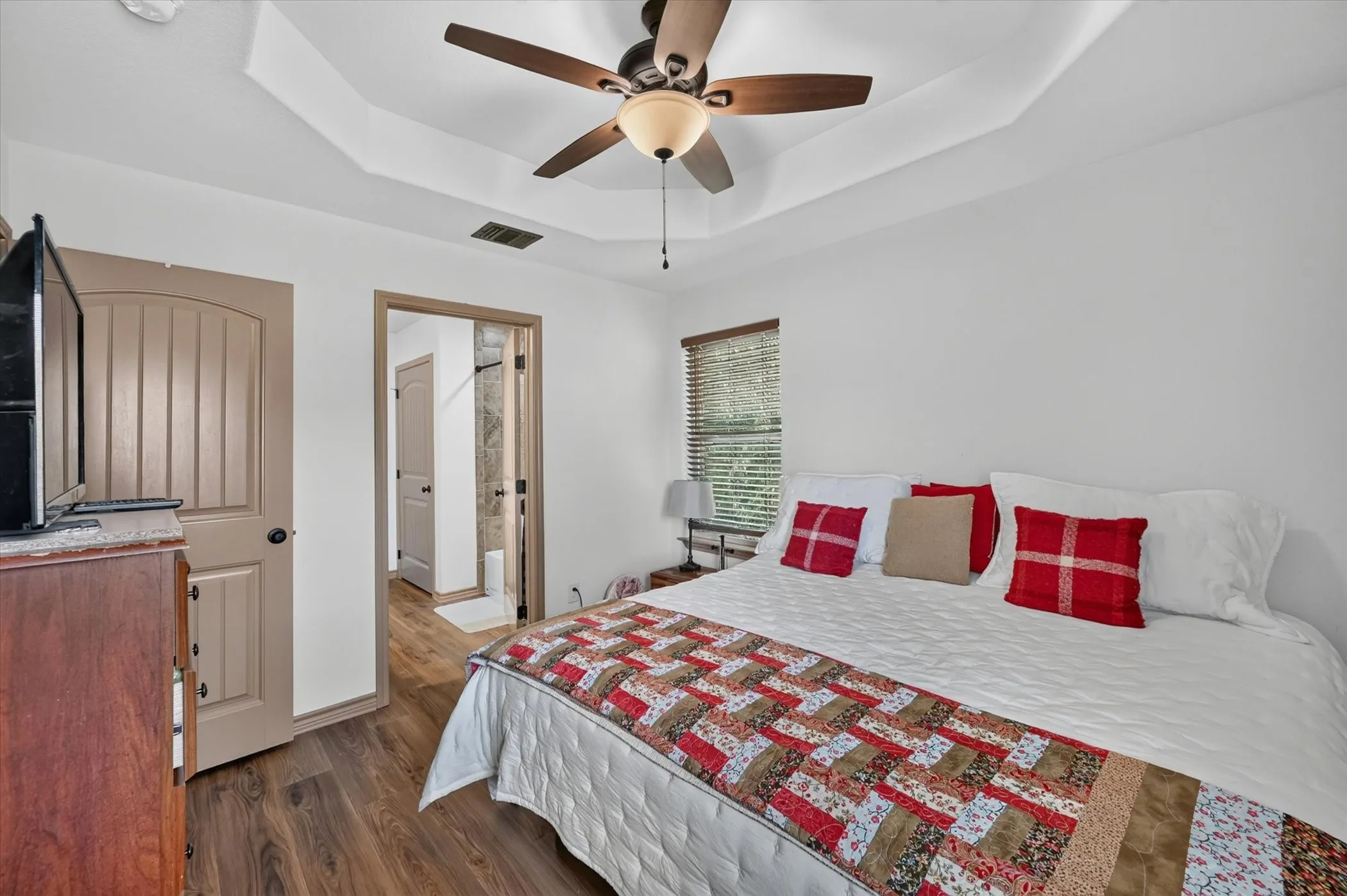 Room featuring wood-finish flooring and a tray ceiling with a ceiling fan