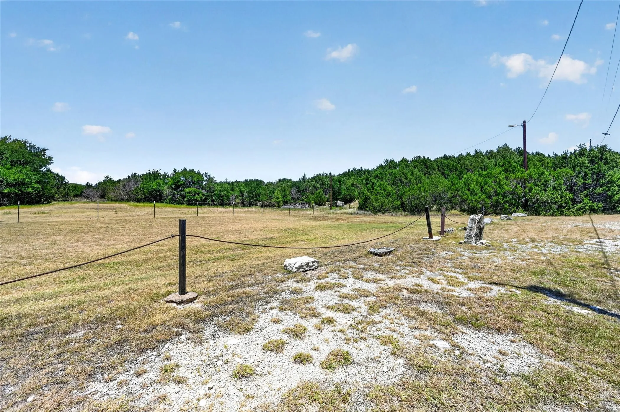 Expansive open land featuring a partial rope fence and scattered natural rock elements