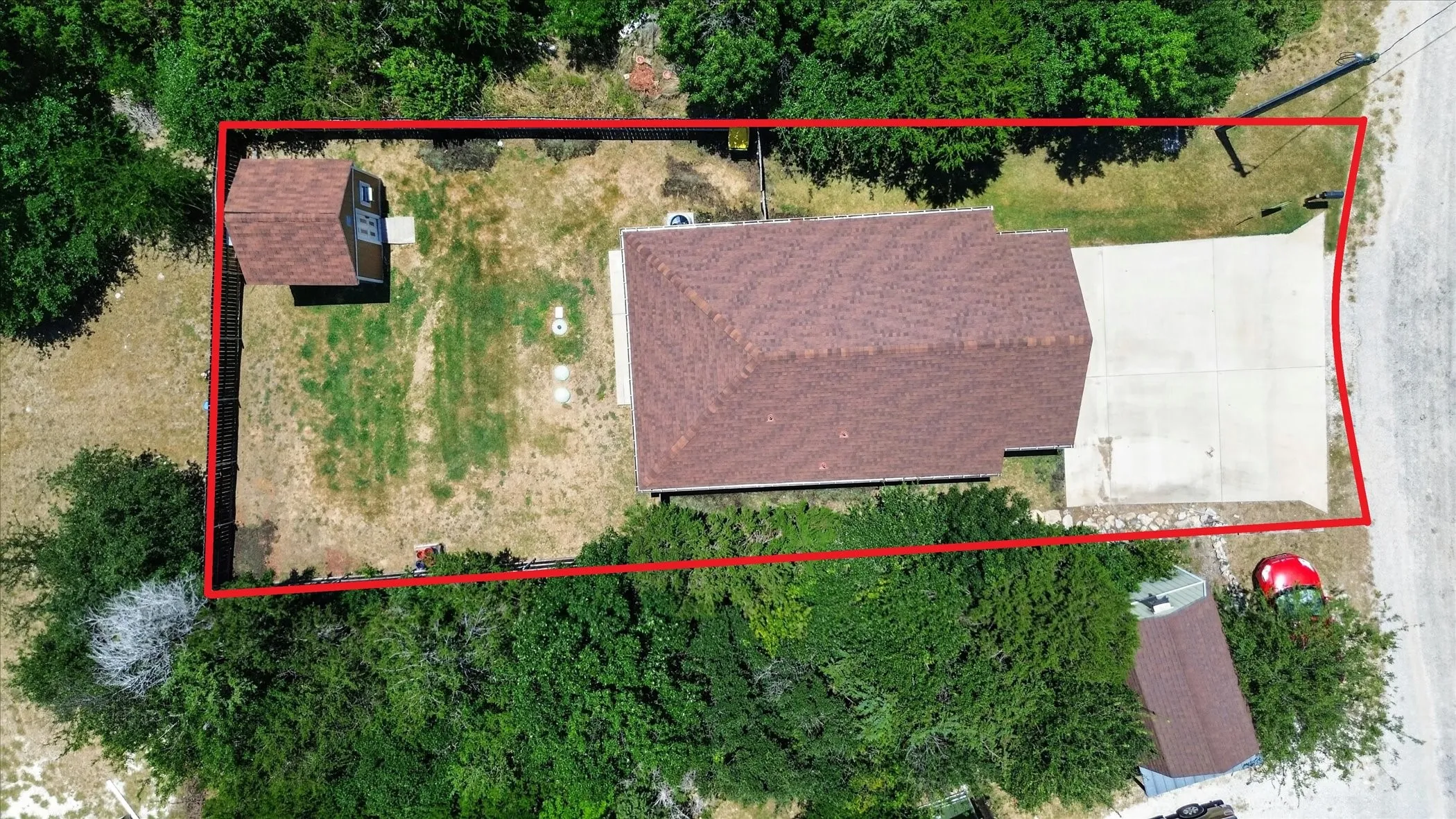 Aerial perspective showcasing a property with a brown shingle roof and a concrete driveway