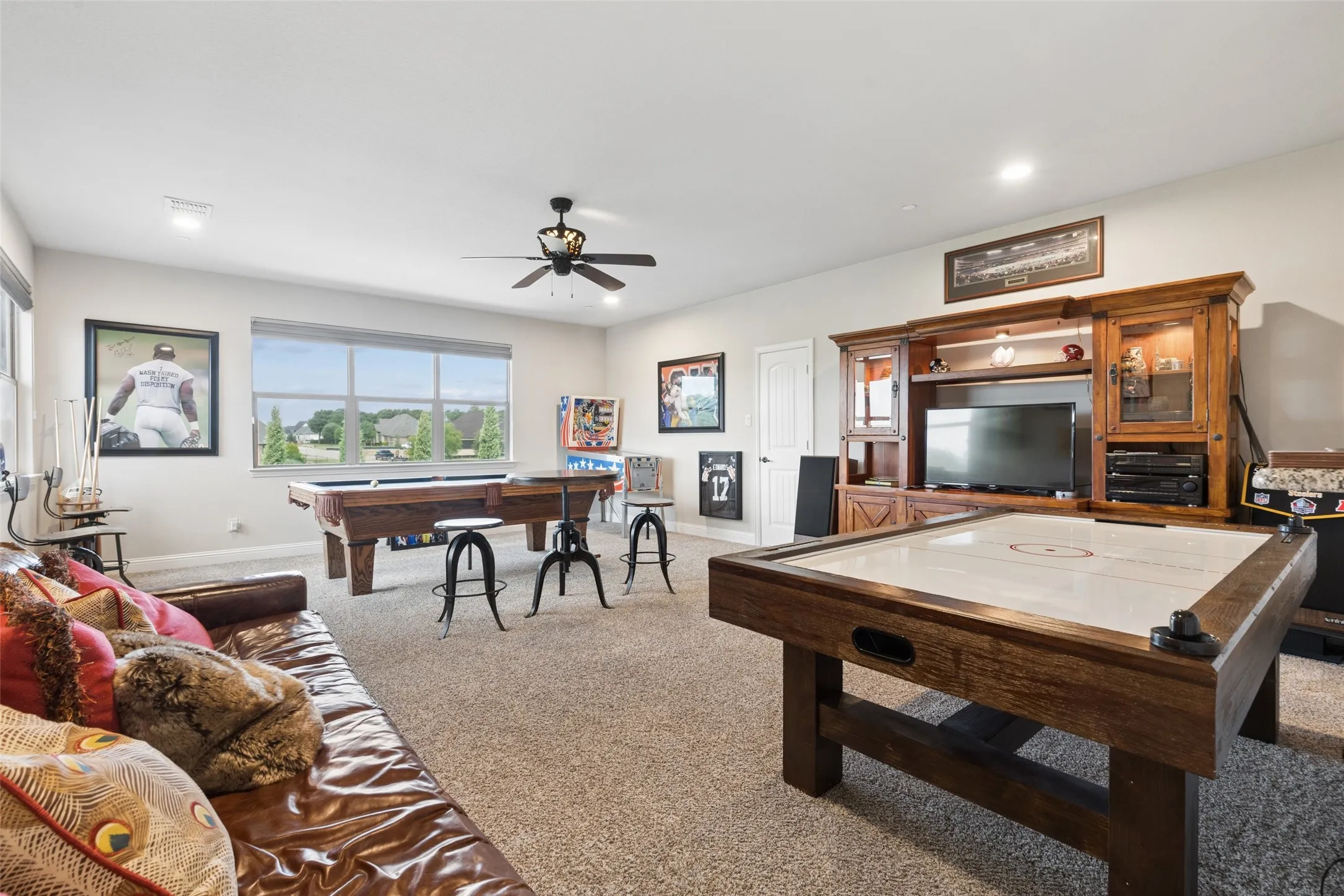 Spacious recreation room featuring neutral carpeting, recessed lighting, and a ceiling fan