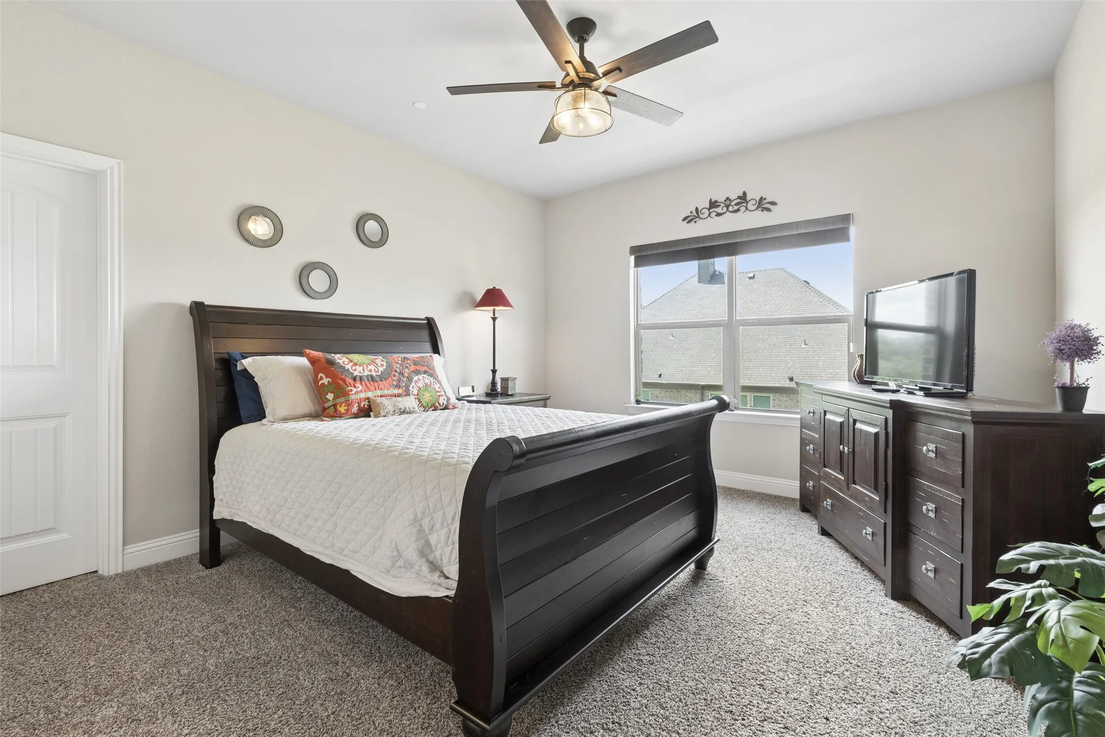 Carpeted room featuring a ceiling fan with integrated lighting, a window with a roller shade, and a white paneled door