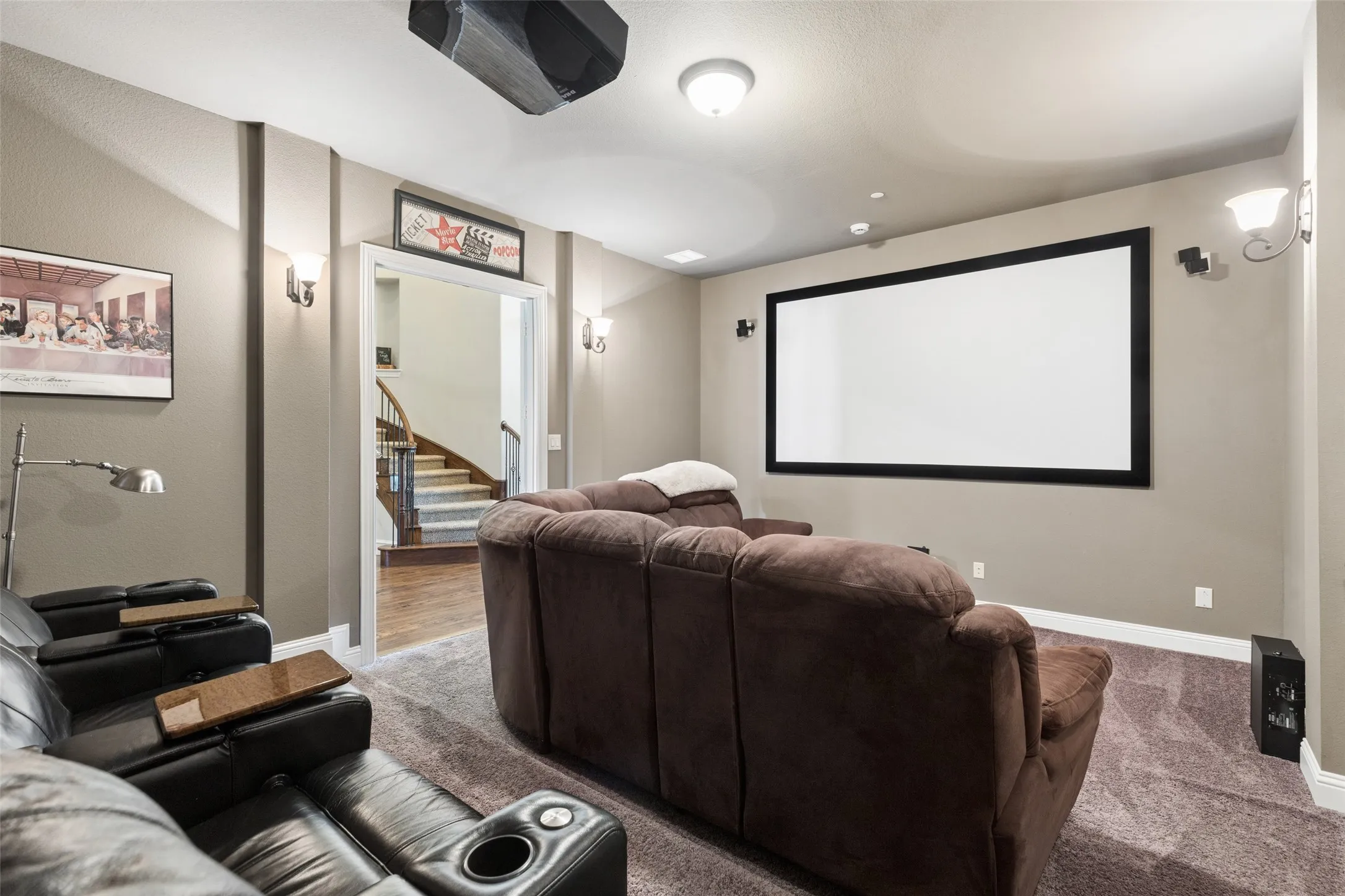 Dedicated media room featuring a large projection screen, wall-mounted projector, and integrated sound system