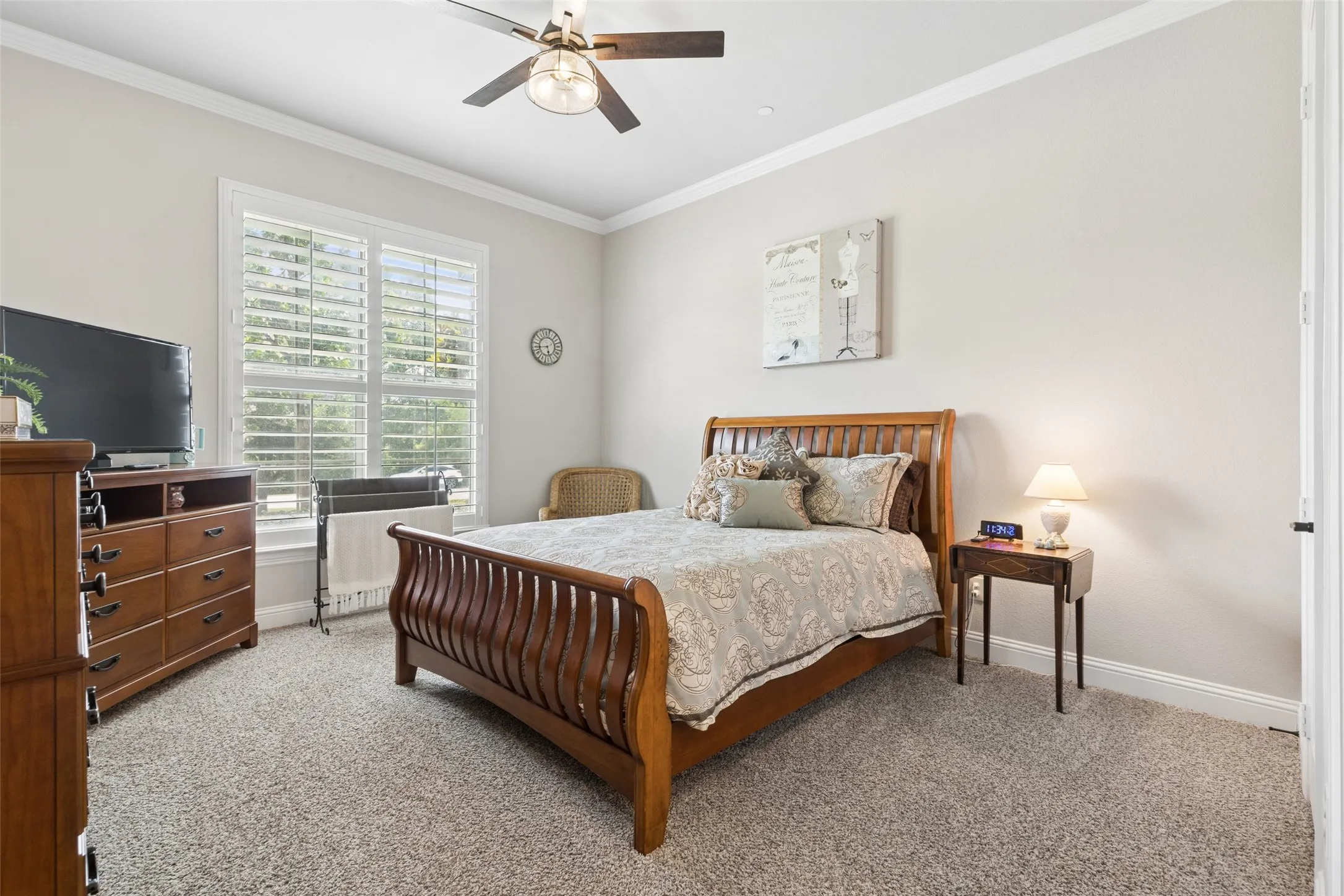 Carpeted room featuring a ceiling fan with integrated lighting, crown molding, and white trim