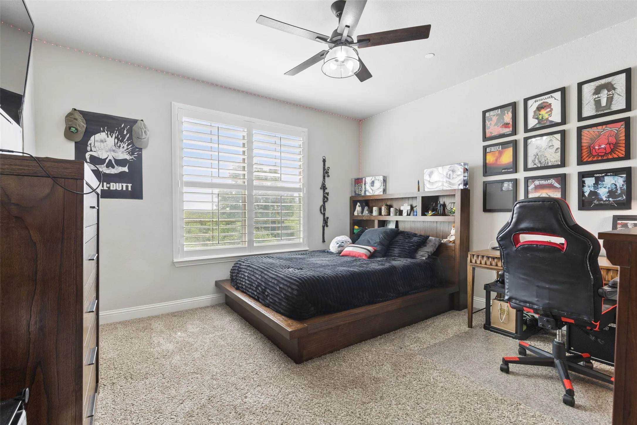 Carpeted room featuring a ceiling fan with integrated lighting, a window with plantation shutters, and crown molding