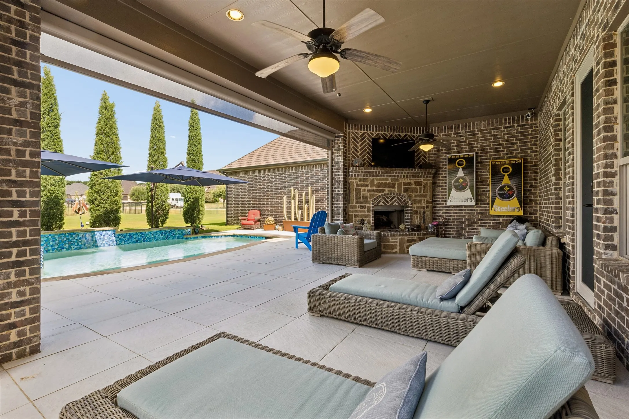 Covered patio featuring a stone fireplace, brick accent wall, recessed lighting, and ceiling fans